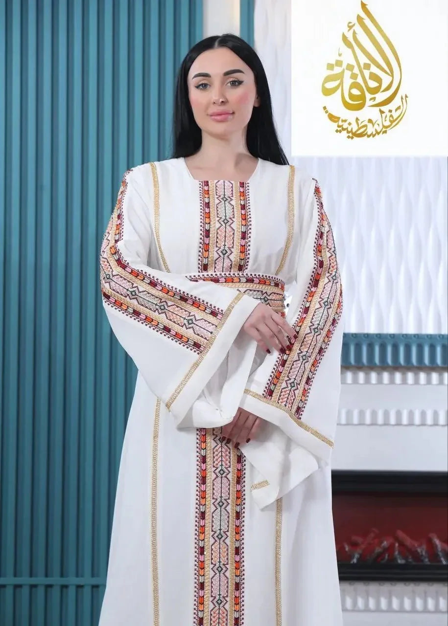 White embroidered Palestinian kaftan with colorful geometric patterns worn by woman from Palestinian Elegance