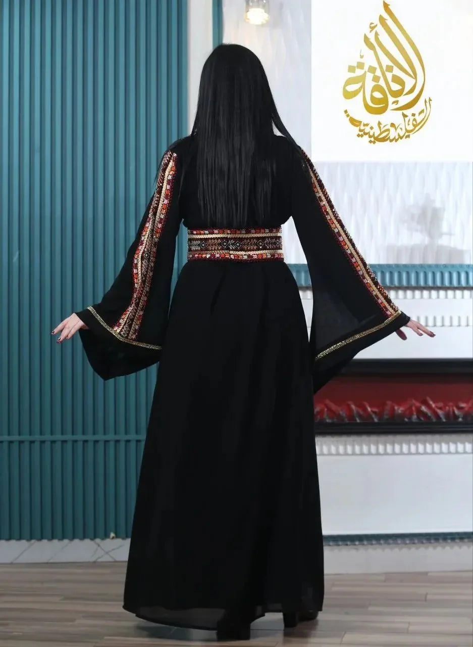 Back view of a woman wearing an embroidered Palestinian kaftan with colorful detailed sleeves and belt