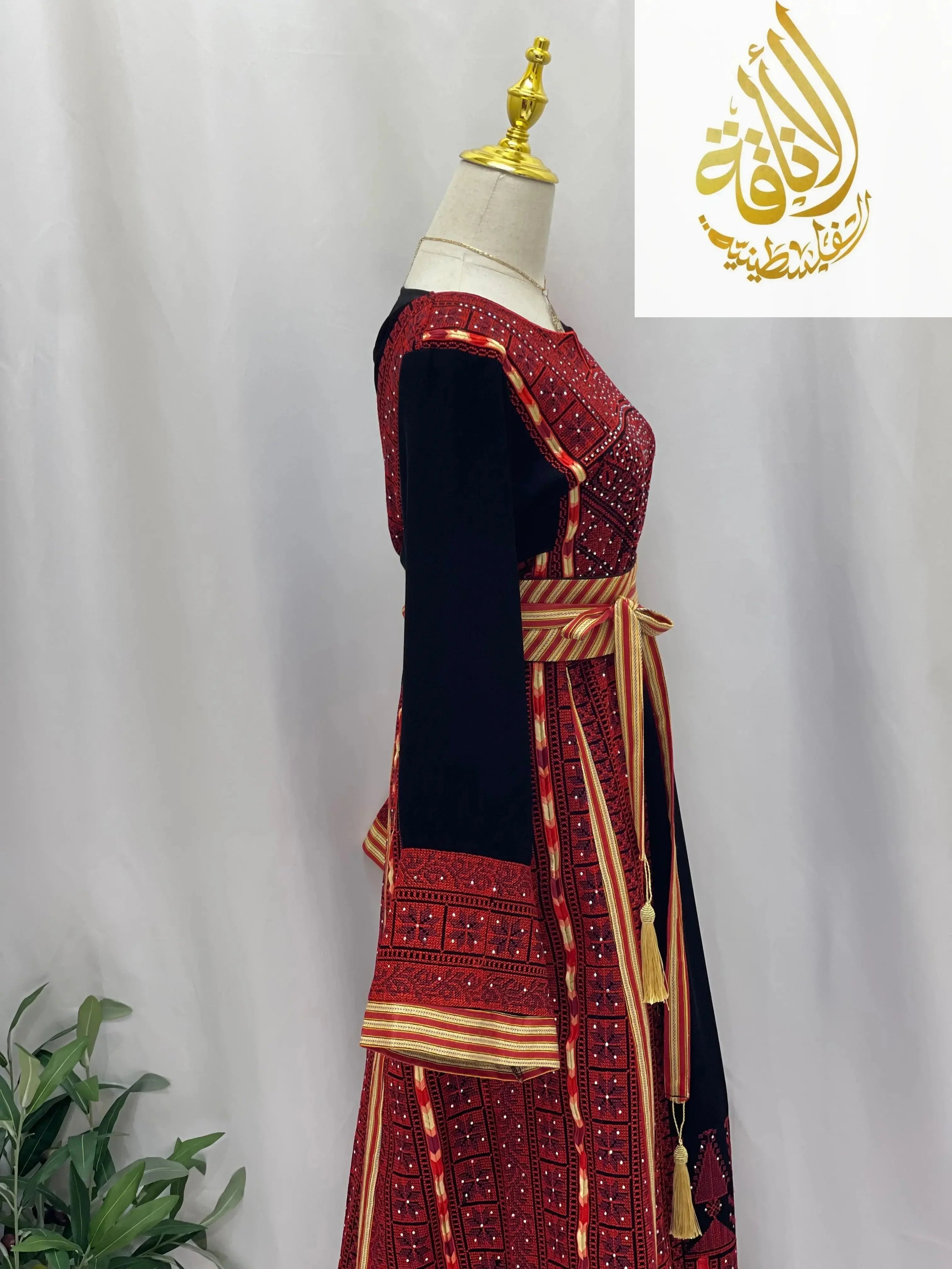Embroidered Palestinian thoub dress with intricate red and black traditional patterns on mannequin