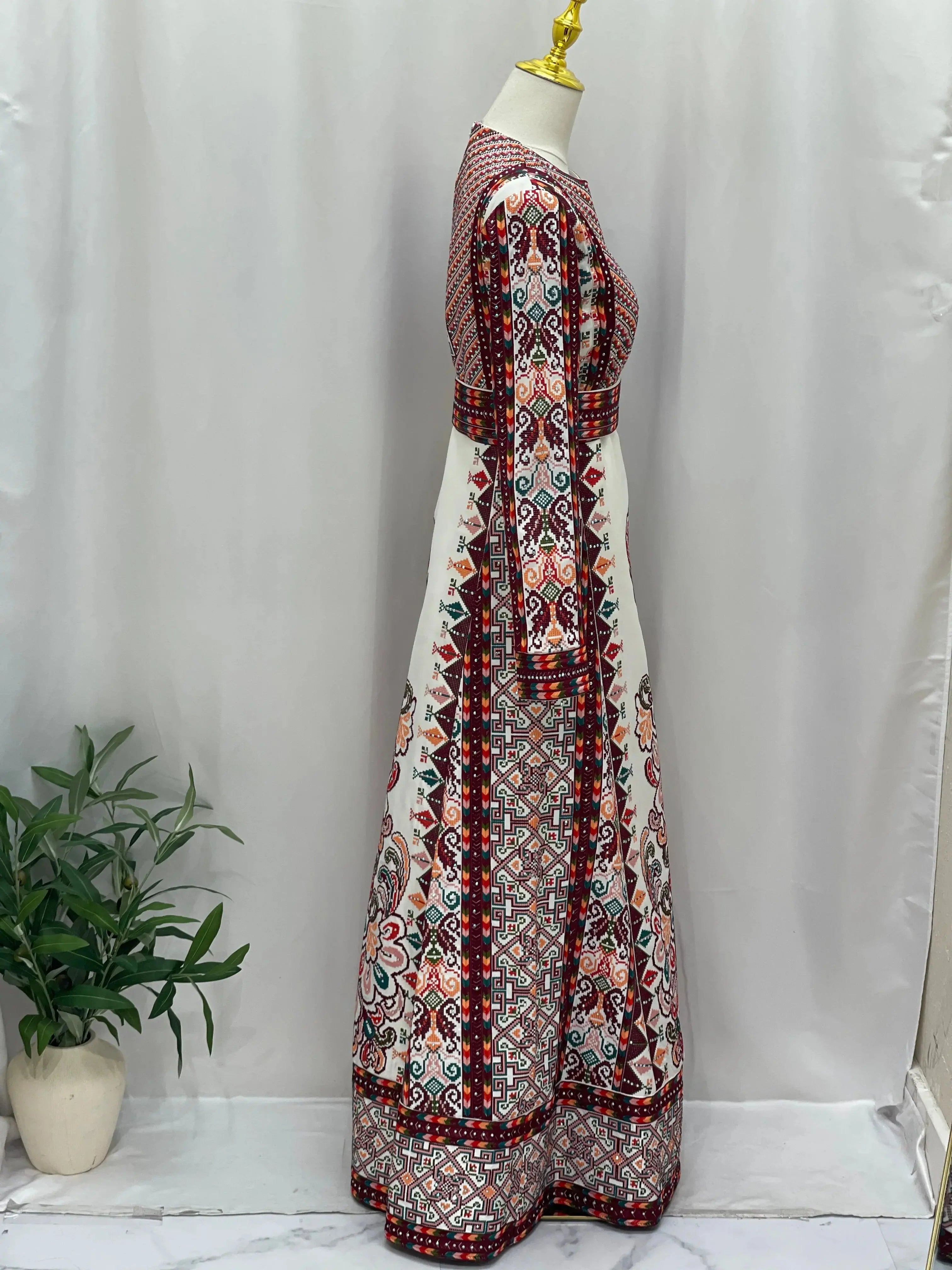 Side view of white Palestinian bridal thoub with intricate red and black embroidery on mannequin