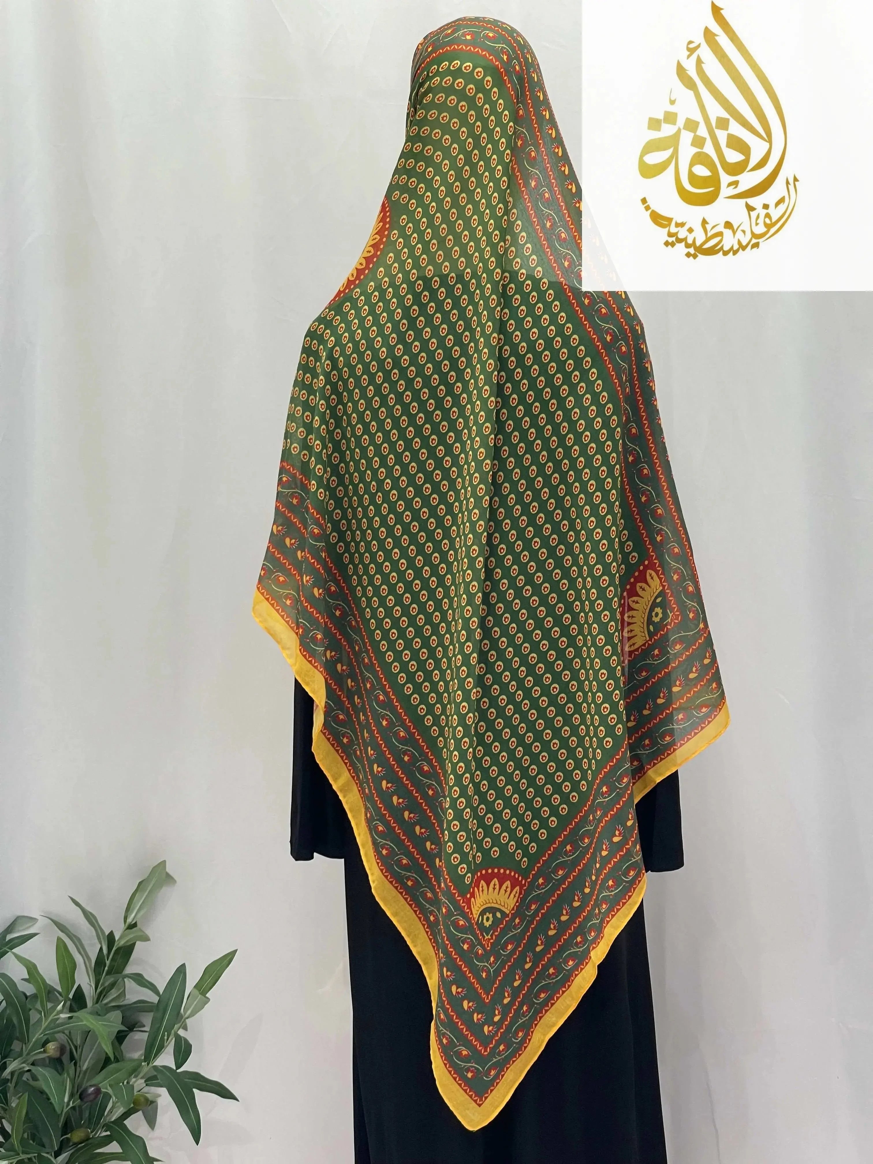 Palestinian Elegance Long Siti Asba Hijab in green with yellow and orange patterned design draped over a black outfit