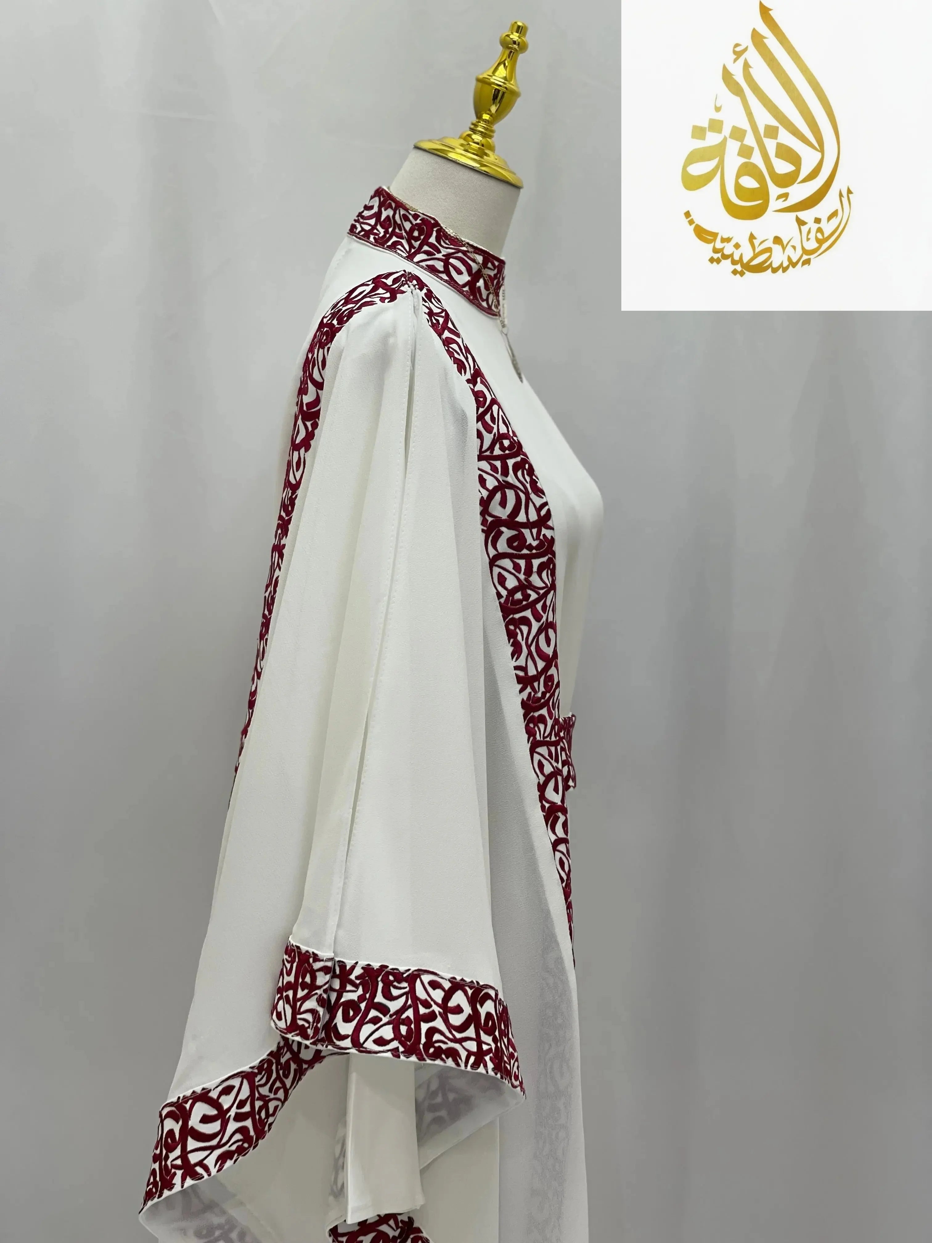White embroidered abaya with Arabic letters in maroon detailing on collar and edges by Palestinian Elegance