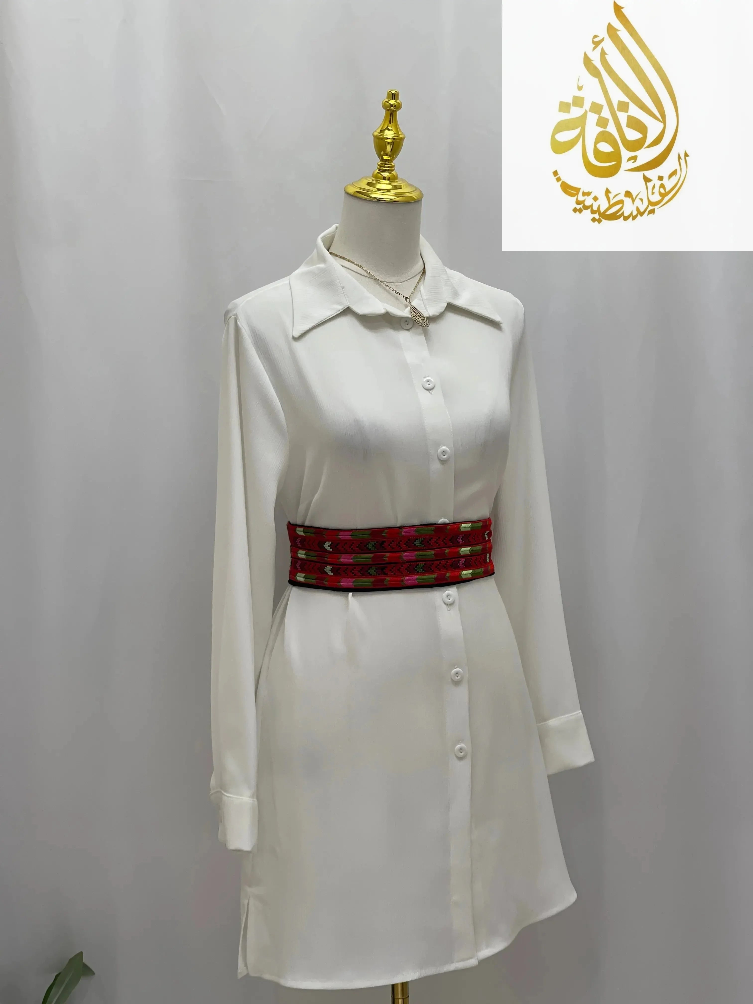 Embroidered Heritage Belt by Palestinian Elegance styled with a white button-up dress on a mannequin
