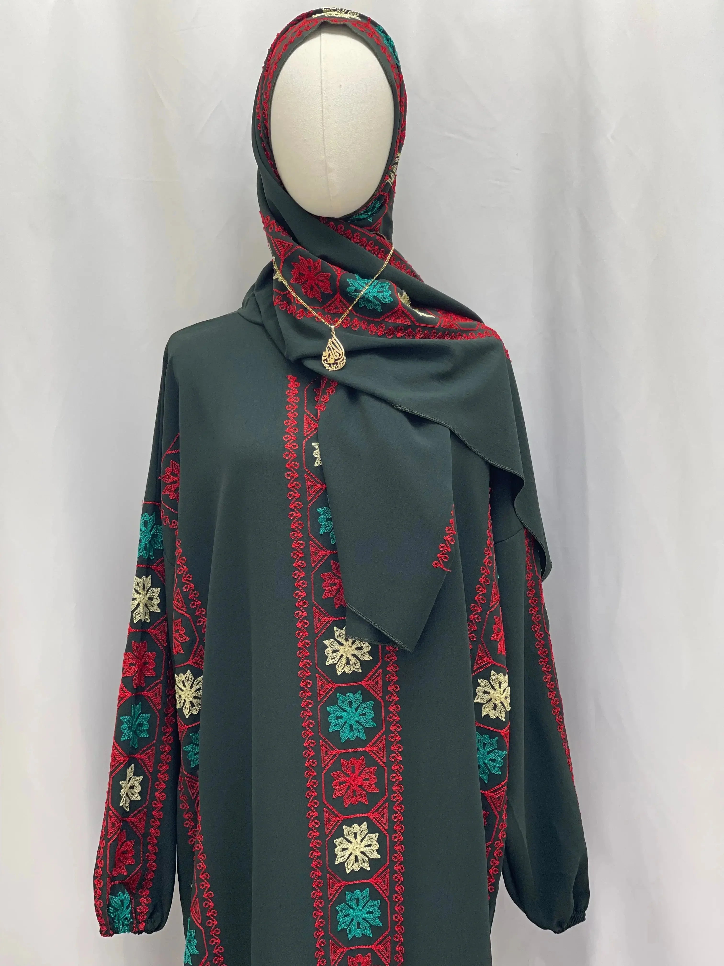 Palestinian Elegance embroidered prayer dress with red, teal, and cream traditional patterns on dark fabric