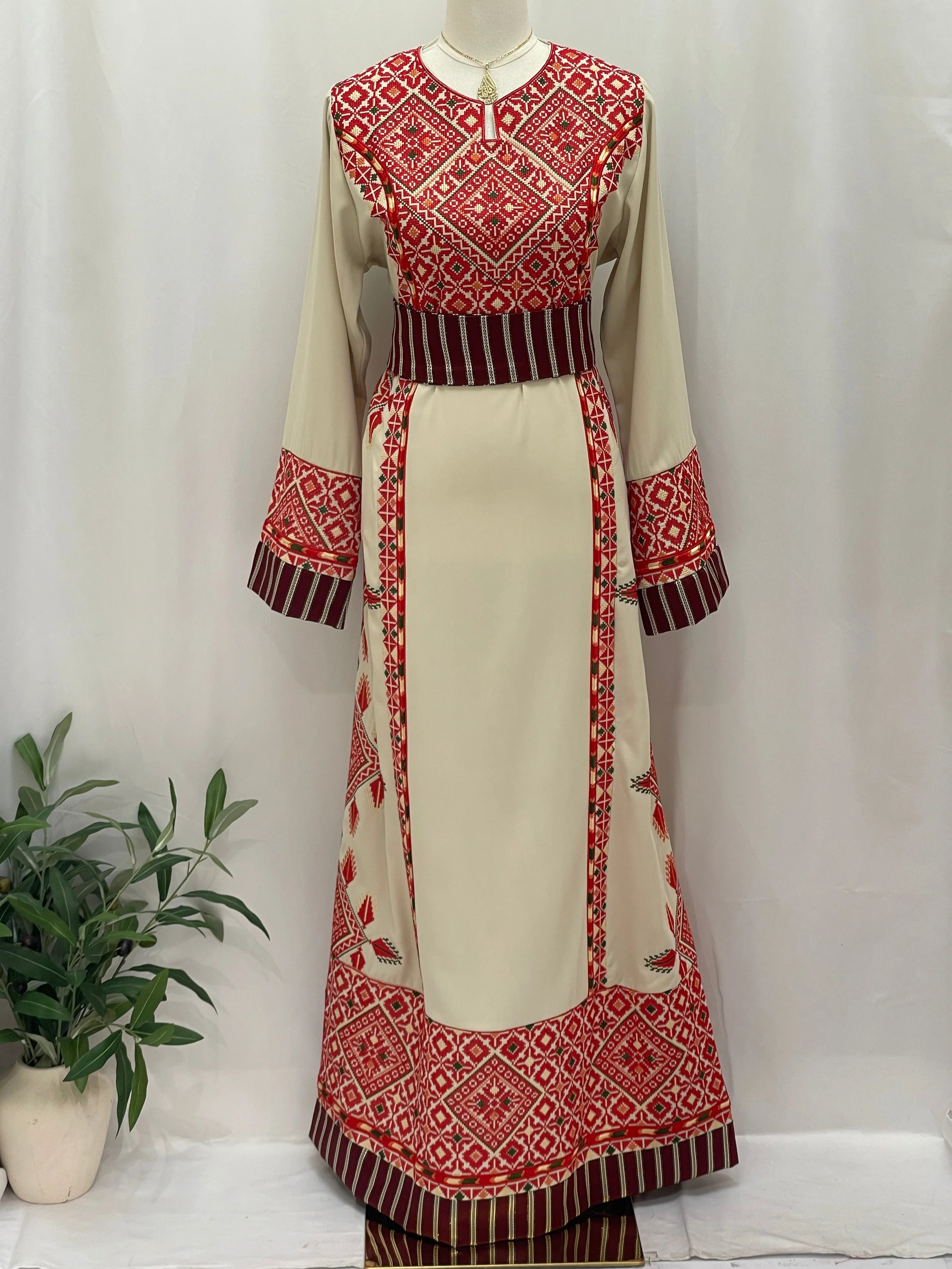 Embroidered Thobe Al-Yamama featuring intricate red and cream patterns with long sleeves and a stylish silhouette