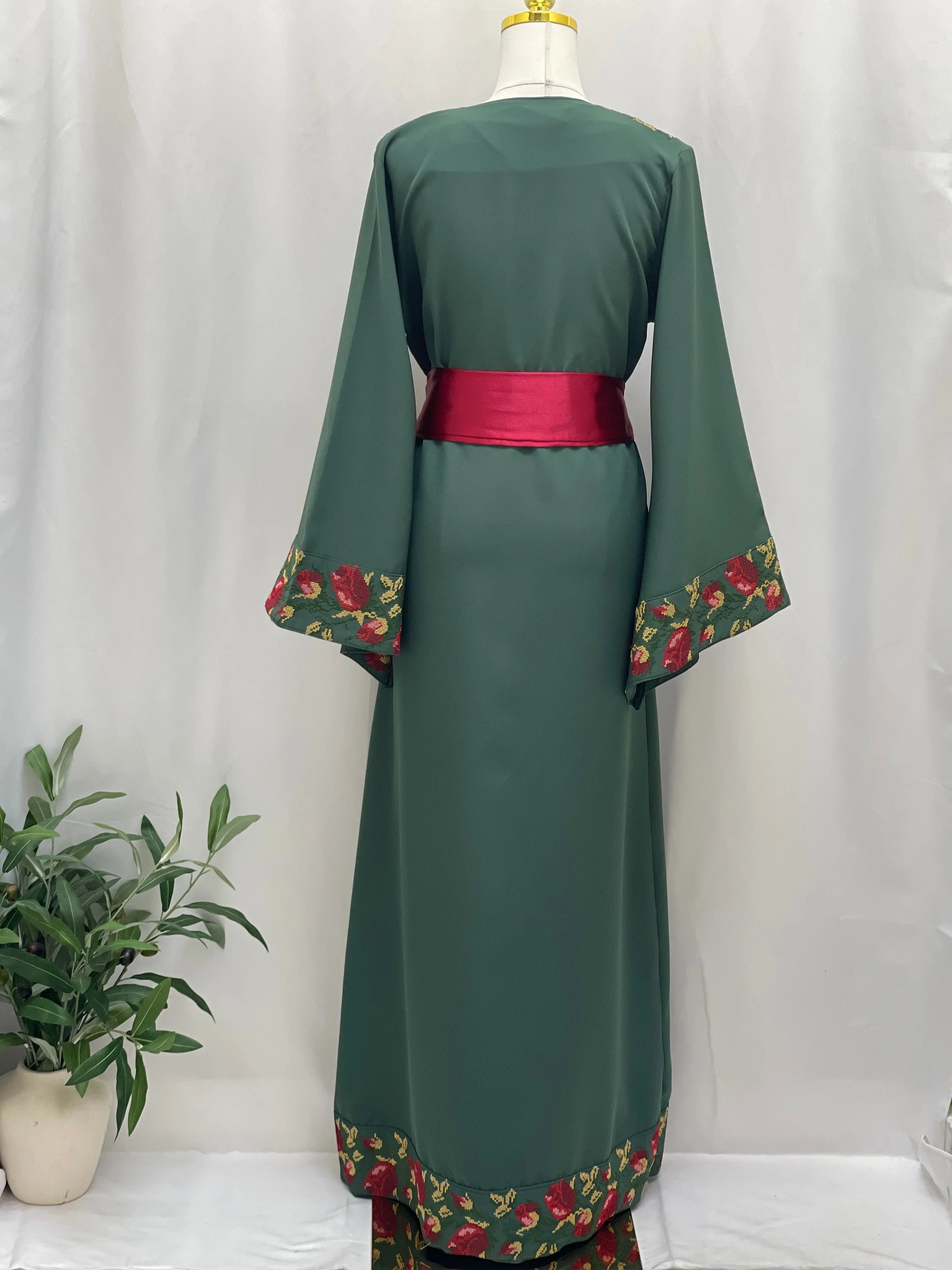 Emerald Blossom EmbroideredThobe by Palestinian Elegance green back view with red floral embroidery trim and satin sash