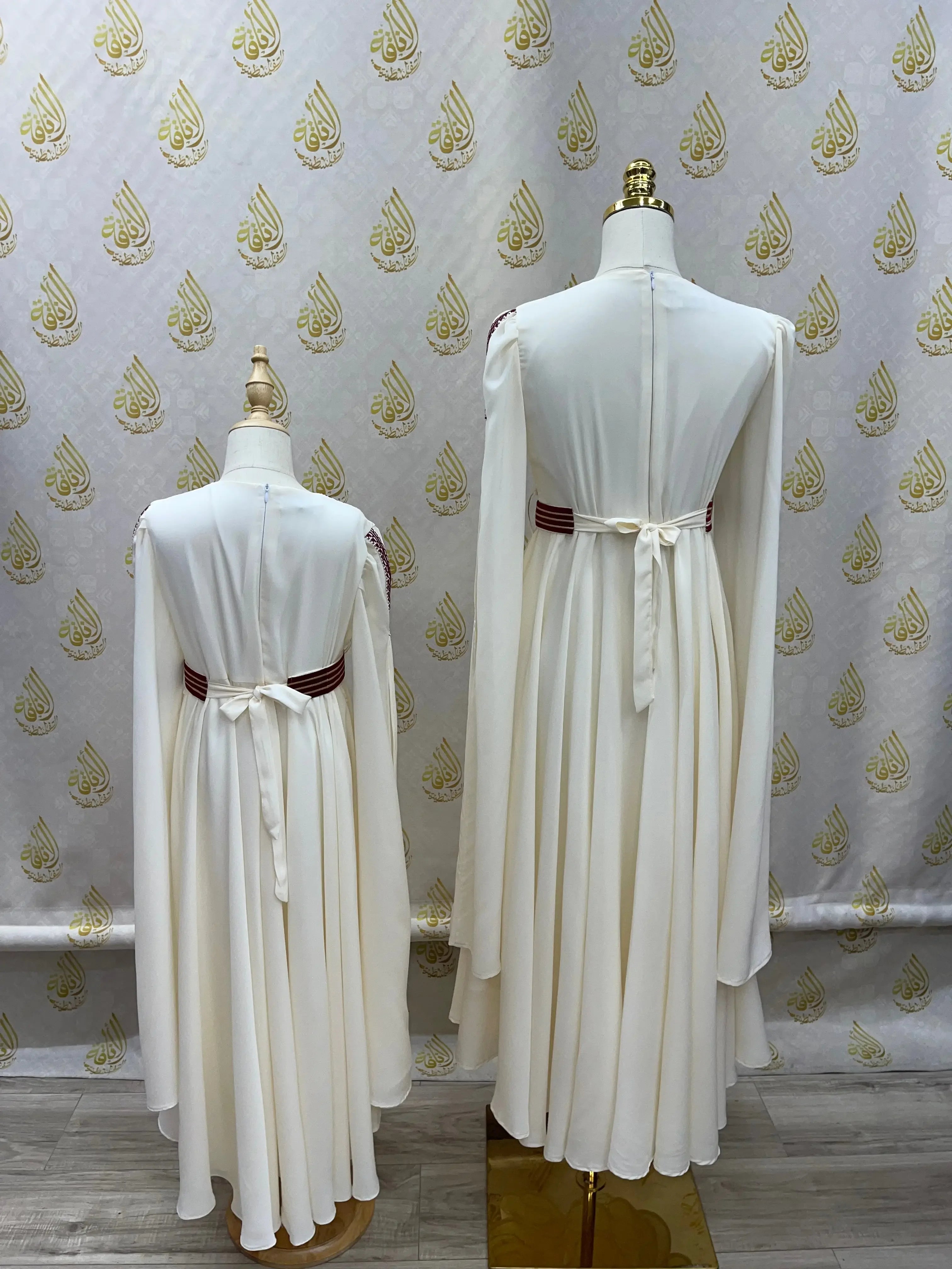 Back view of Palestinian girls embroidered dress in white with long sleeves and waist tie on mannequins by Palestinian Elegance