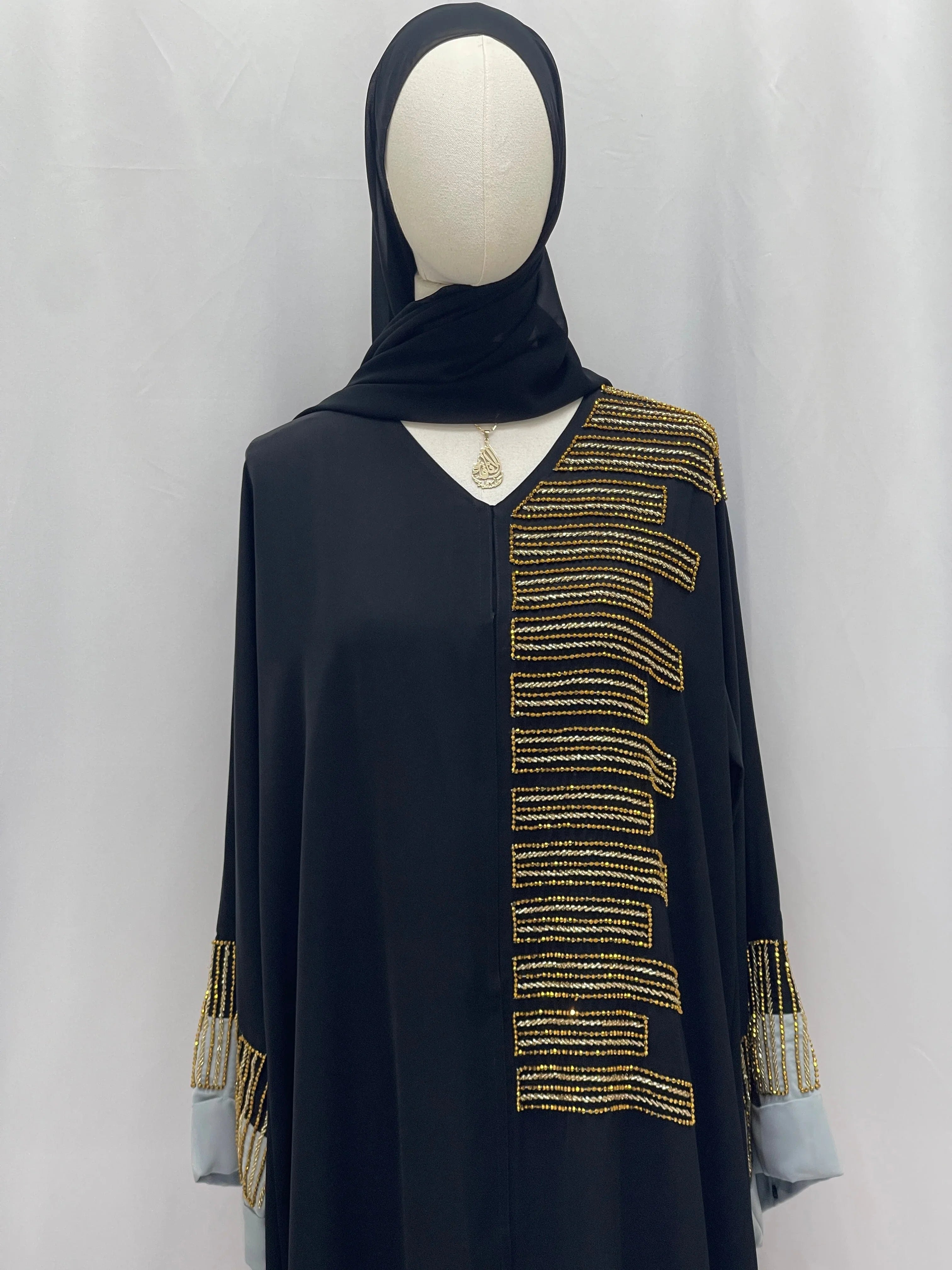 Palestinian Elegance Fancy Beads Dubai Abaya black abaya on mannequin with gold bead embellishments on front and cuffs