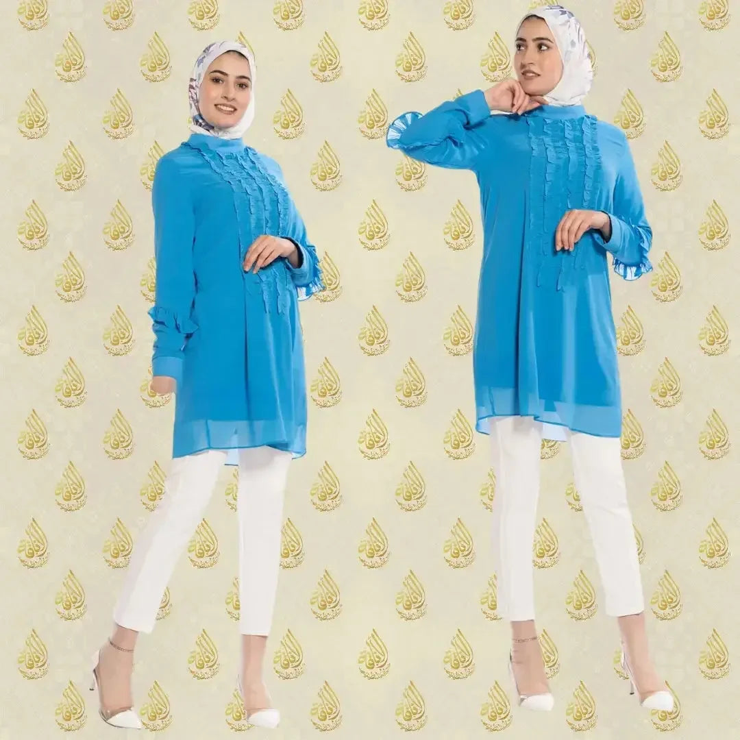 Luxury women's embroidered shirt in bright blue by Palestinian Elegance worn with white pants