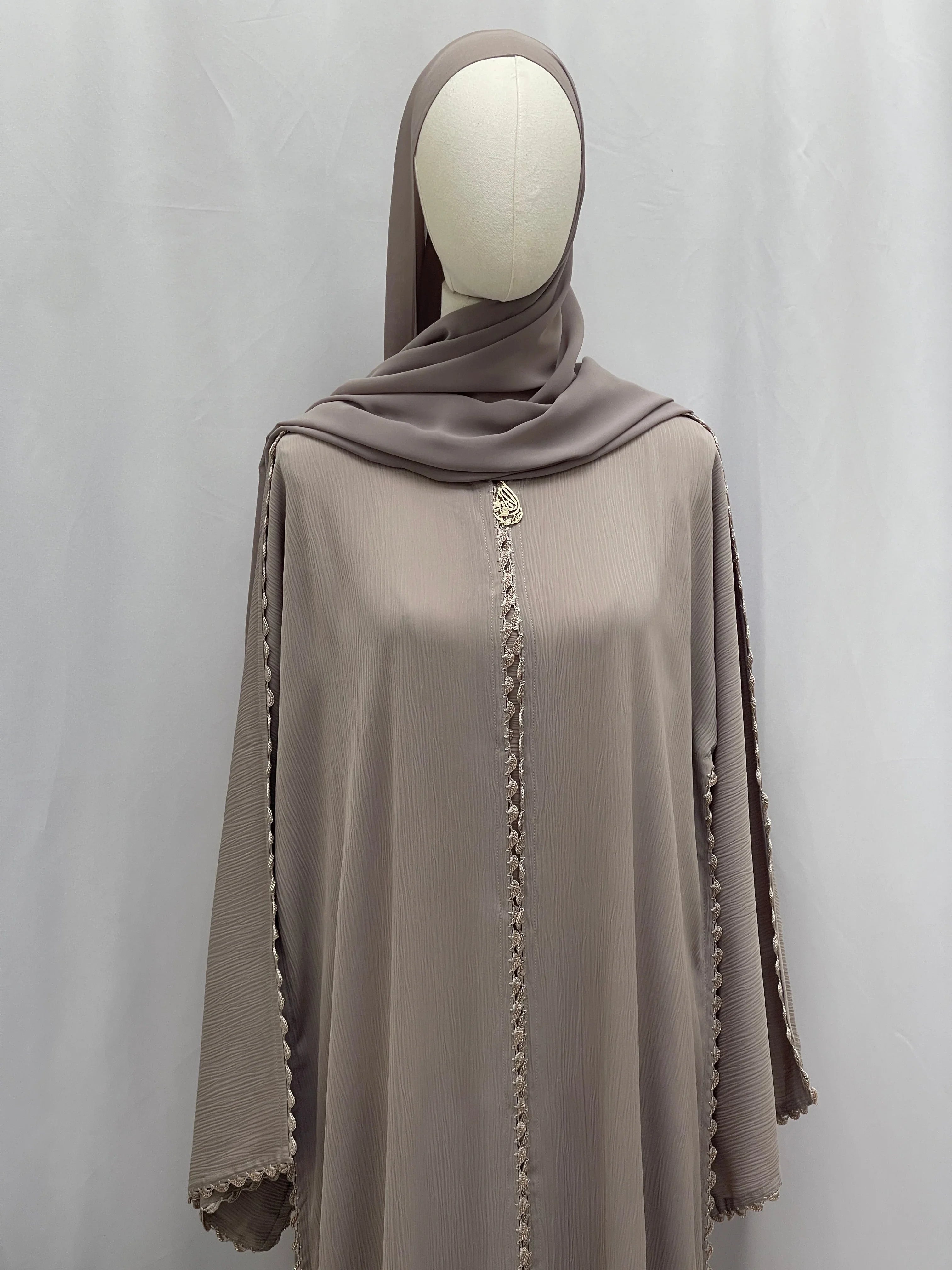 Palestinian Elegance Ghosoon Abaya in taupe with intricate trim on front and sleeves displayed on mannequin