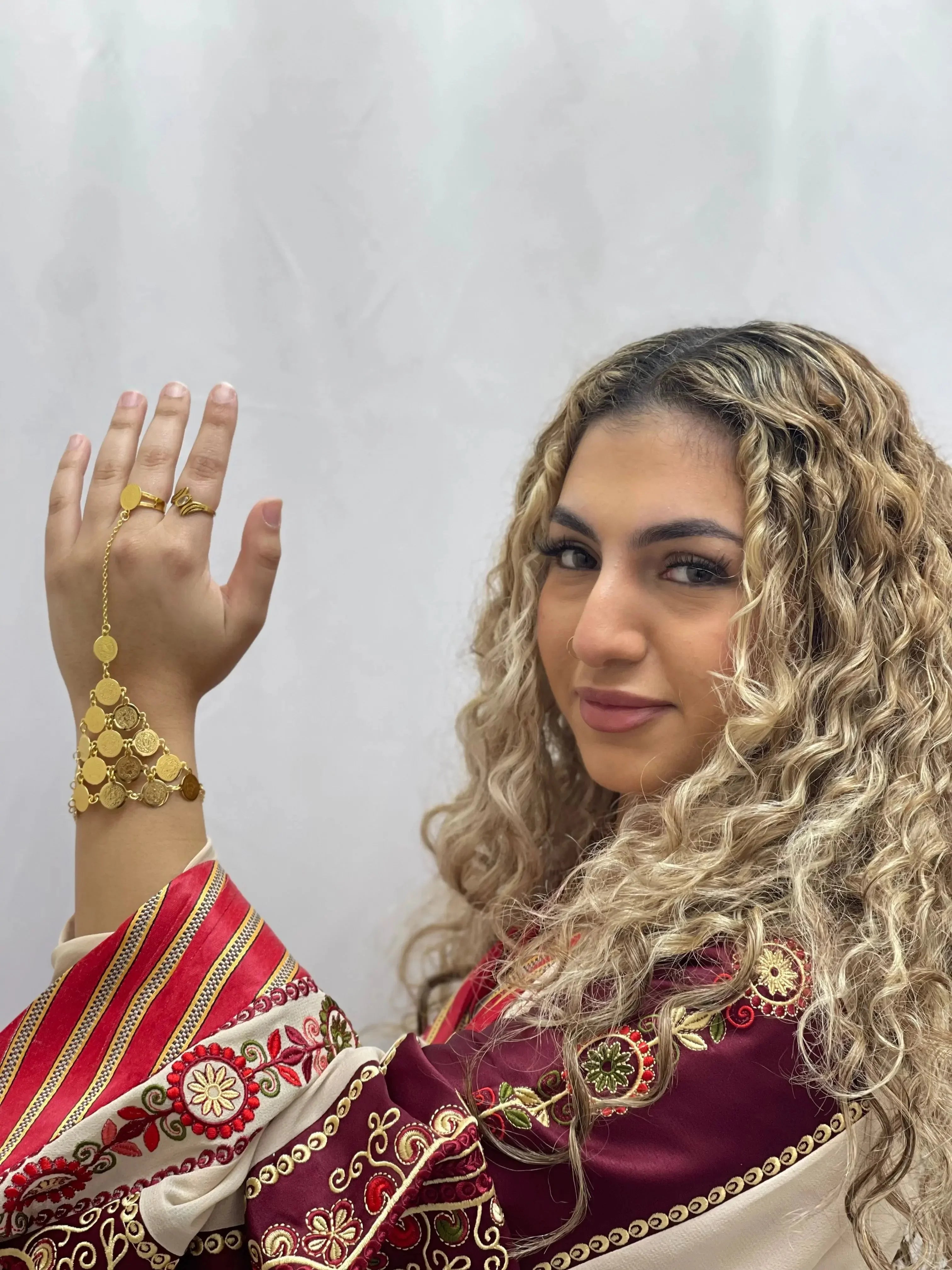 Woman wearing gold kaff hand jewelry with traditional embroidered Palestinian attire