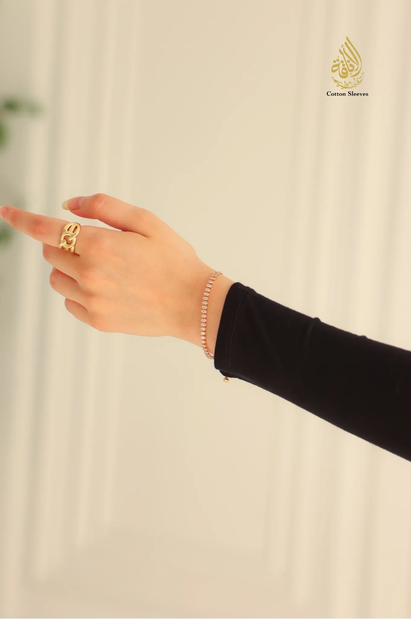 Hand wearing a gold ring on a beige background