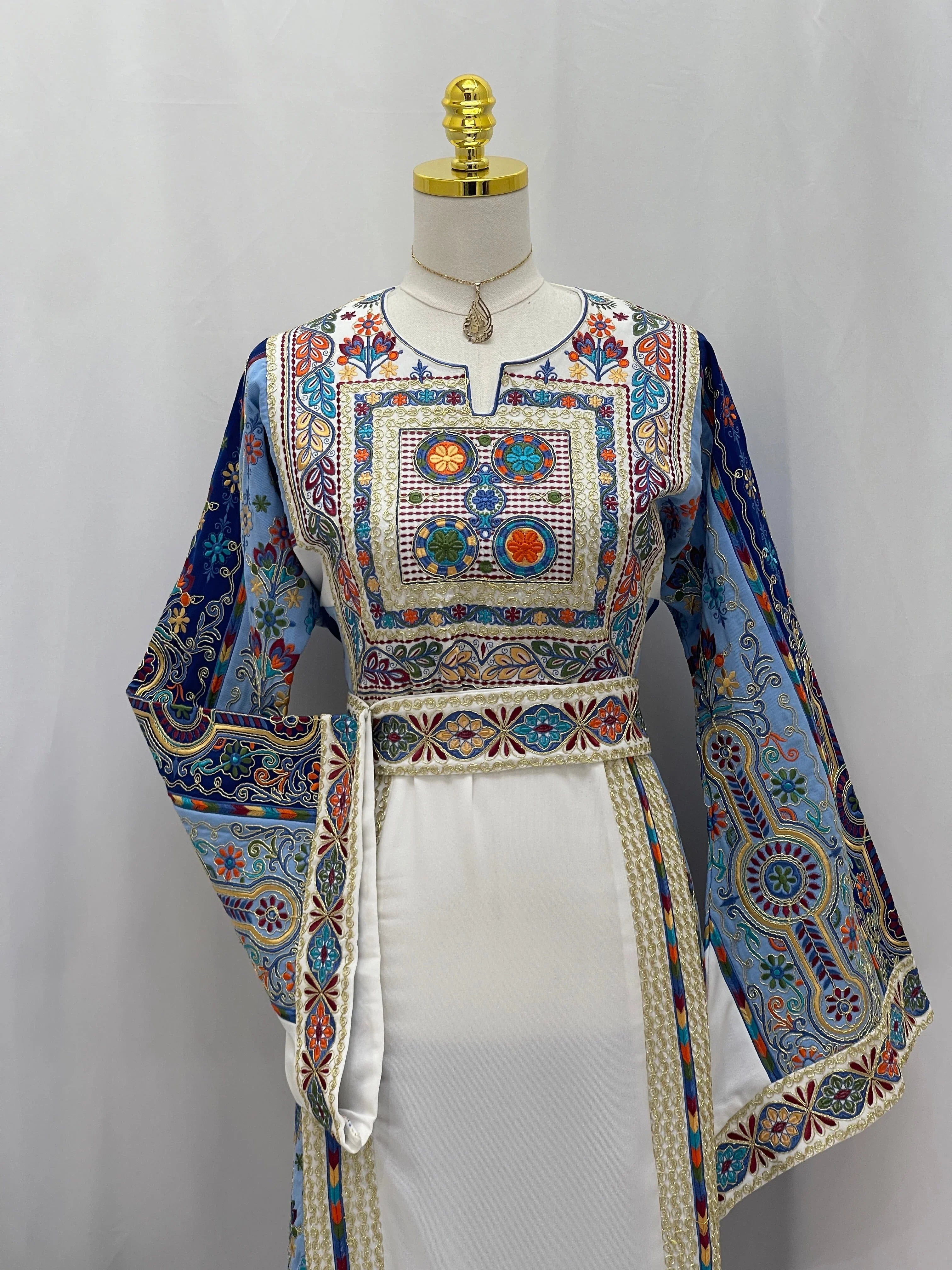 Heavenly Blossoms Thobe by Palestinian Elegance embroidered white dress with blue floral panels and ornate belt