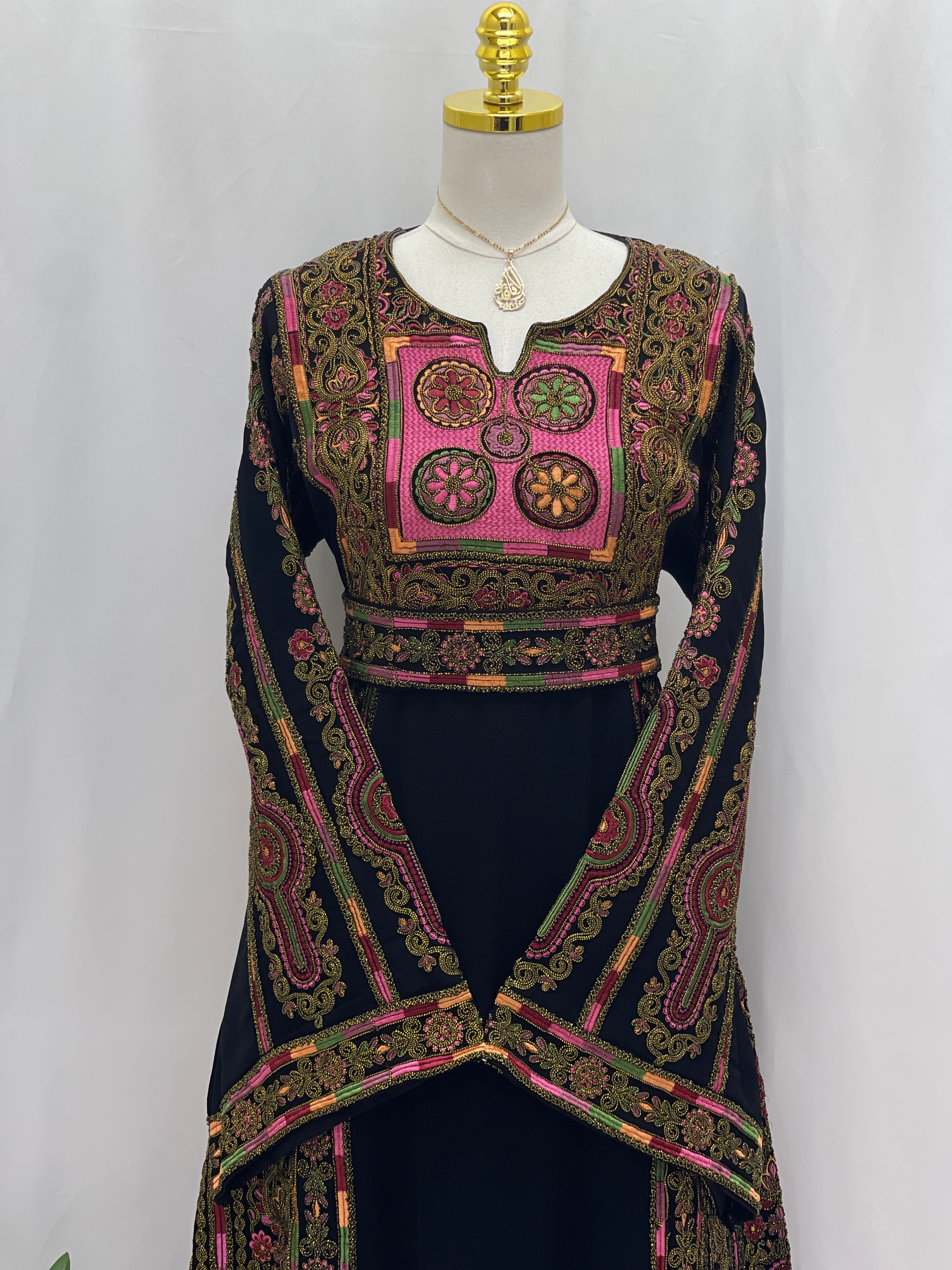 Palestinian Elegance Heritage Glow Bream Embroidered Thoub. Black thobe with pink and gold embroidered panels and bell sleeves