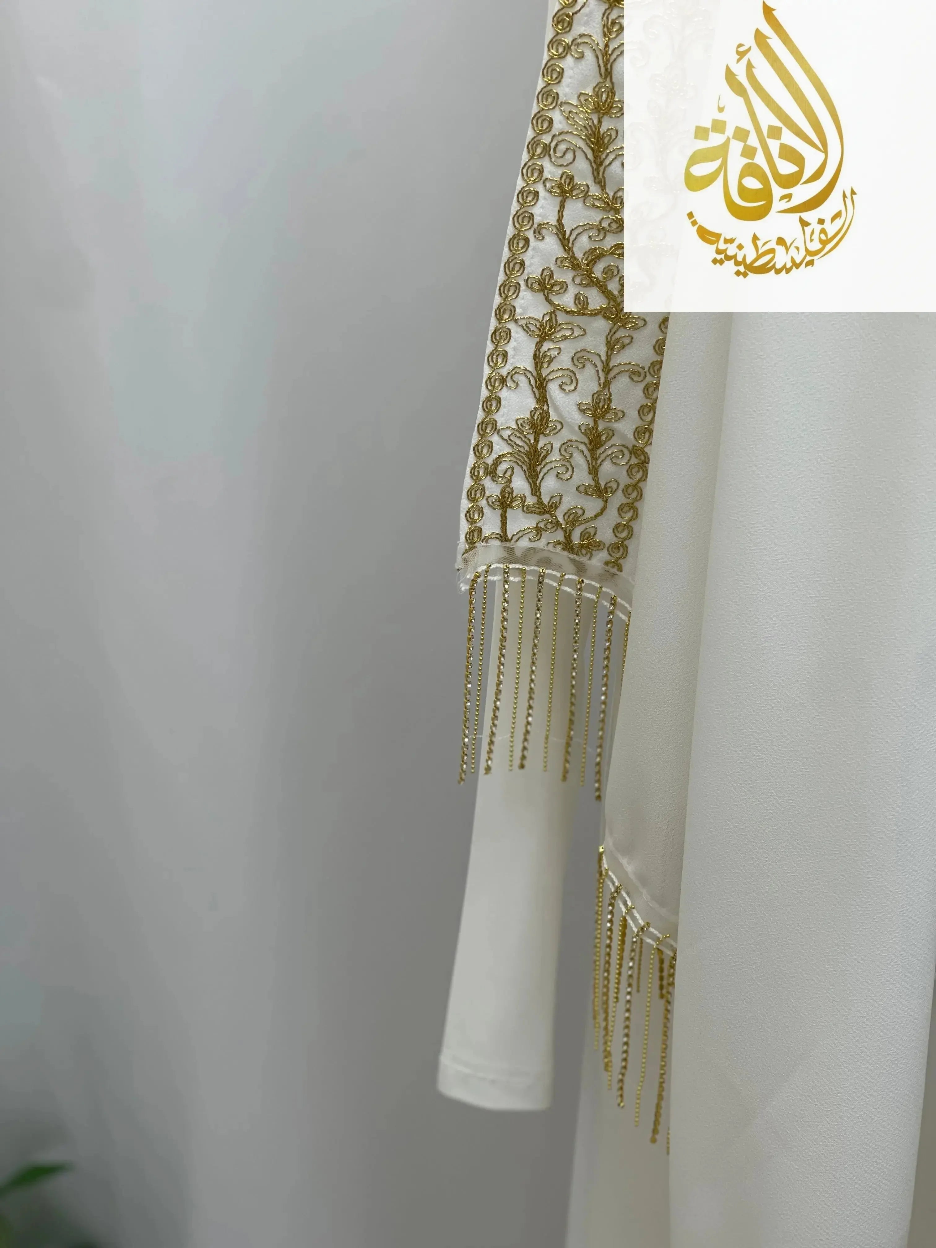 White Palestinian Traditional Modest Fashion Kasab Khirka with intricate golden embroidery and delicate fringe details