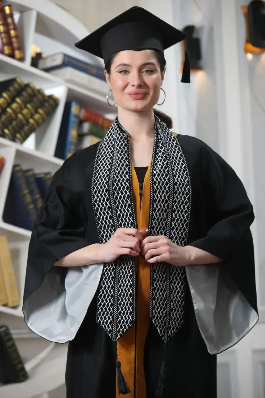 Woman wearing Palestinian keffiyeh graduation stole over black graduation gown and cap indoors