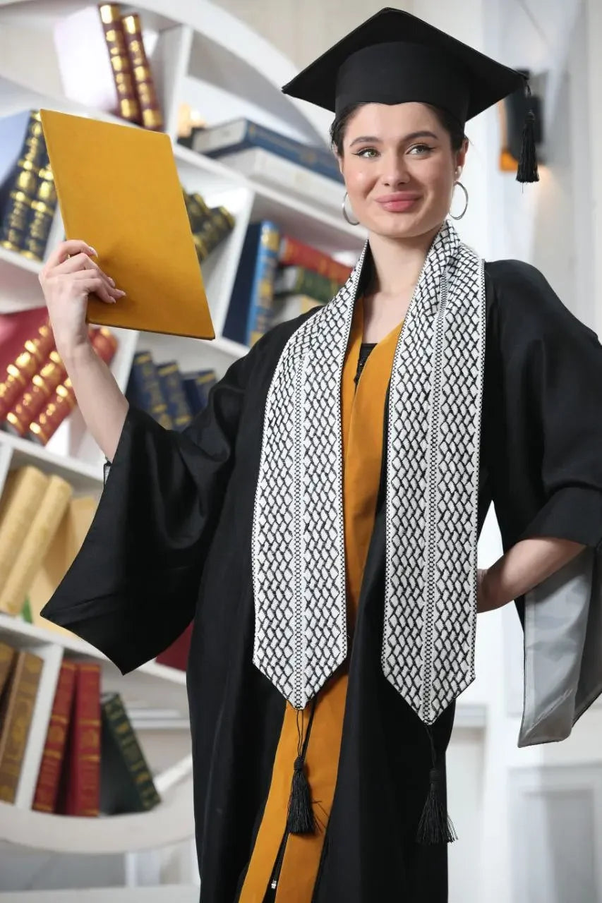 Graduate wearing Palestinian keffiyeh graduation stole with black tassels and a black cap and gown