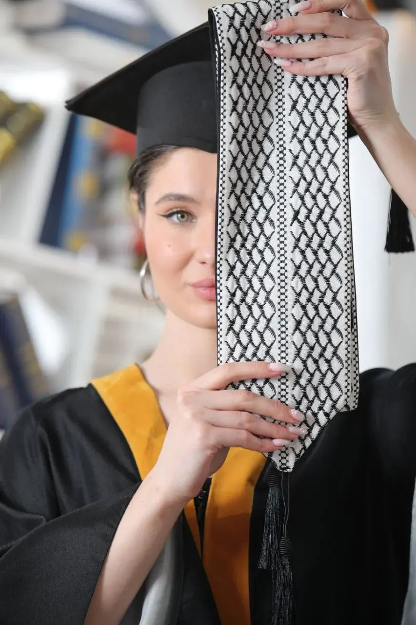 Graduate holding Palestinian keffiyeh graduation stole with traditional black and white pattern