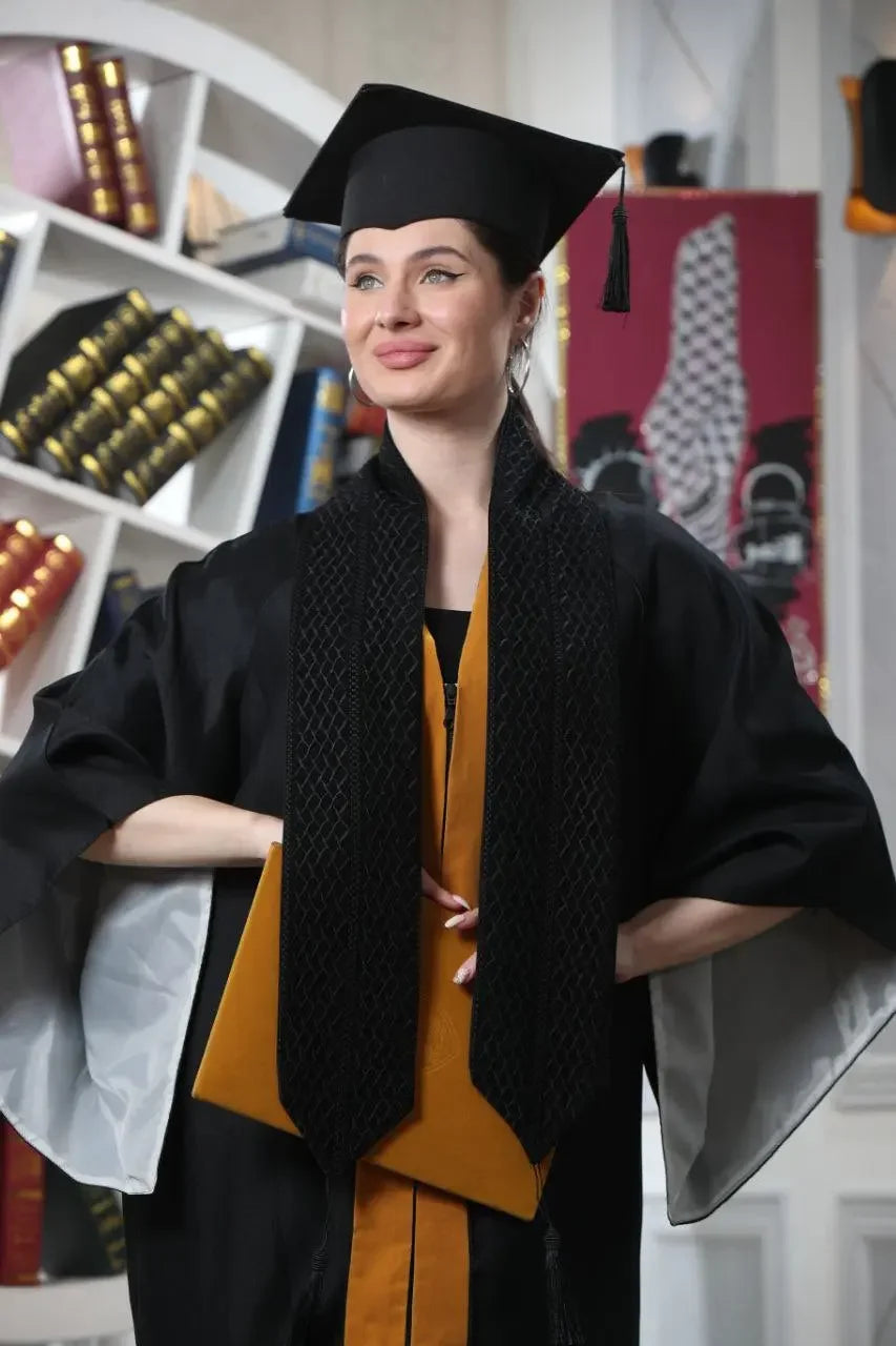 Graduate wearing a Palestinian keffiyeh graduation stole with black and gold academic robe
