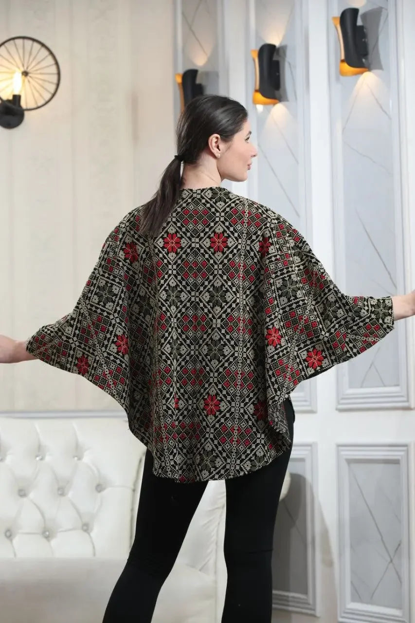 Woman wearing Palestinian tattreez cape with intricate red and black embroidery in a casual setting