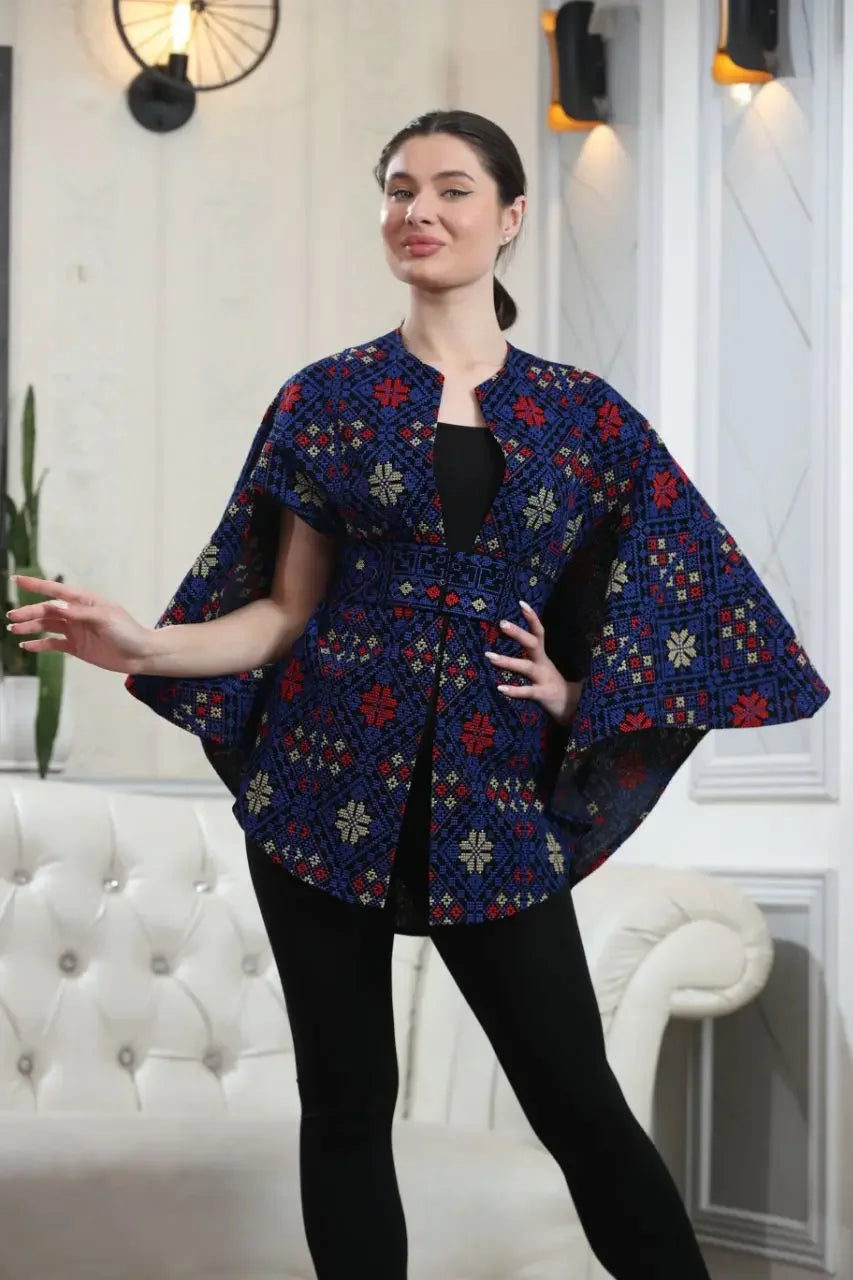 Woman wearing Palestinian tattreez cape by Palestinian Elegance with detailed red and blue embroidery