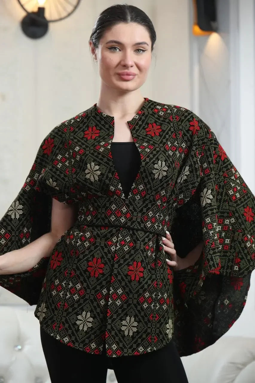 Woman wearing a Palestinian tattreez cape with red and white embroidered floral patterns by Palestinian Elegance