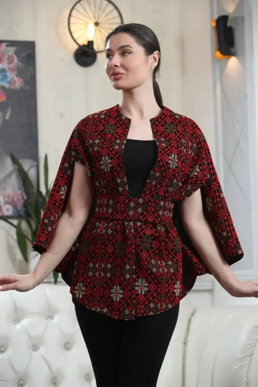Woman wearing a Palestinian tattreez cape with intricate red and black embroidery from Palestinian Elegance