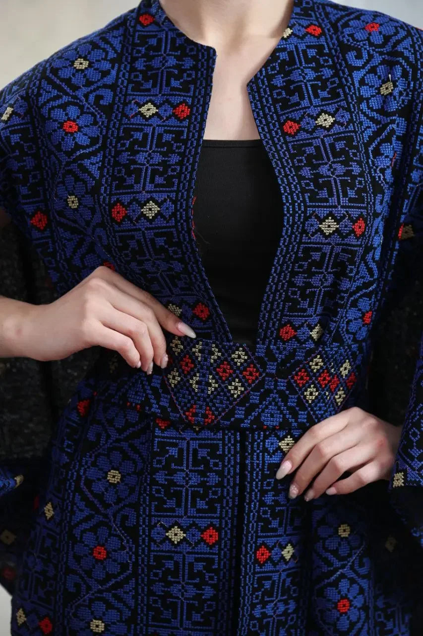 Palestinian embroidered cape in blue with intricate red and beige patterns by Palestinian Elegance