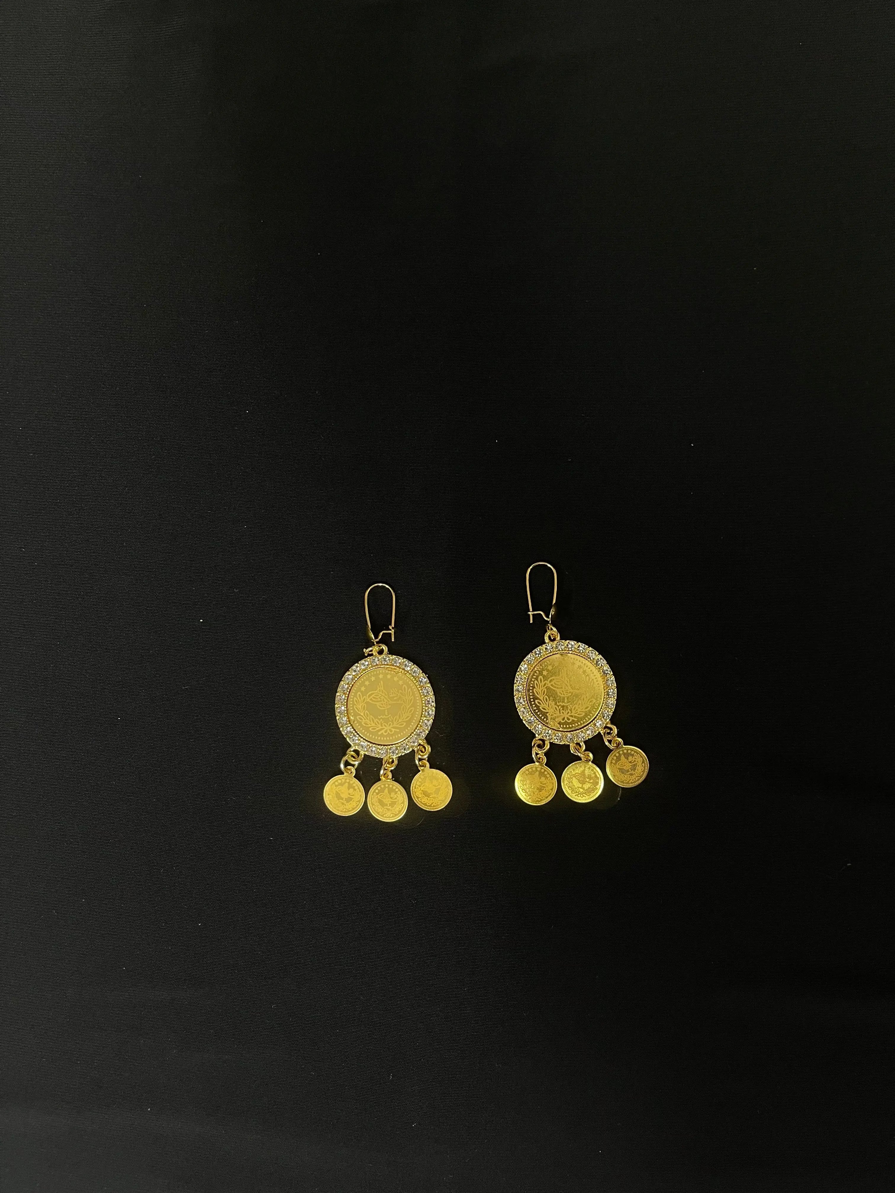 Imitated Gold Earrings by Palestinian Elegance with coin design and dangling charms on black background
