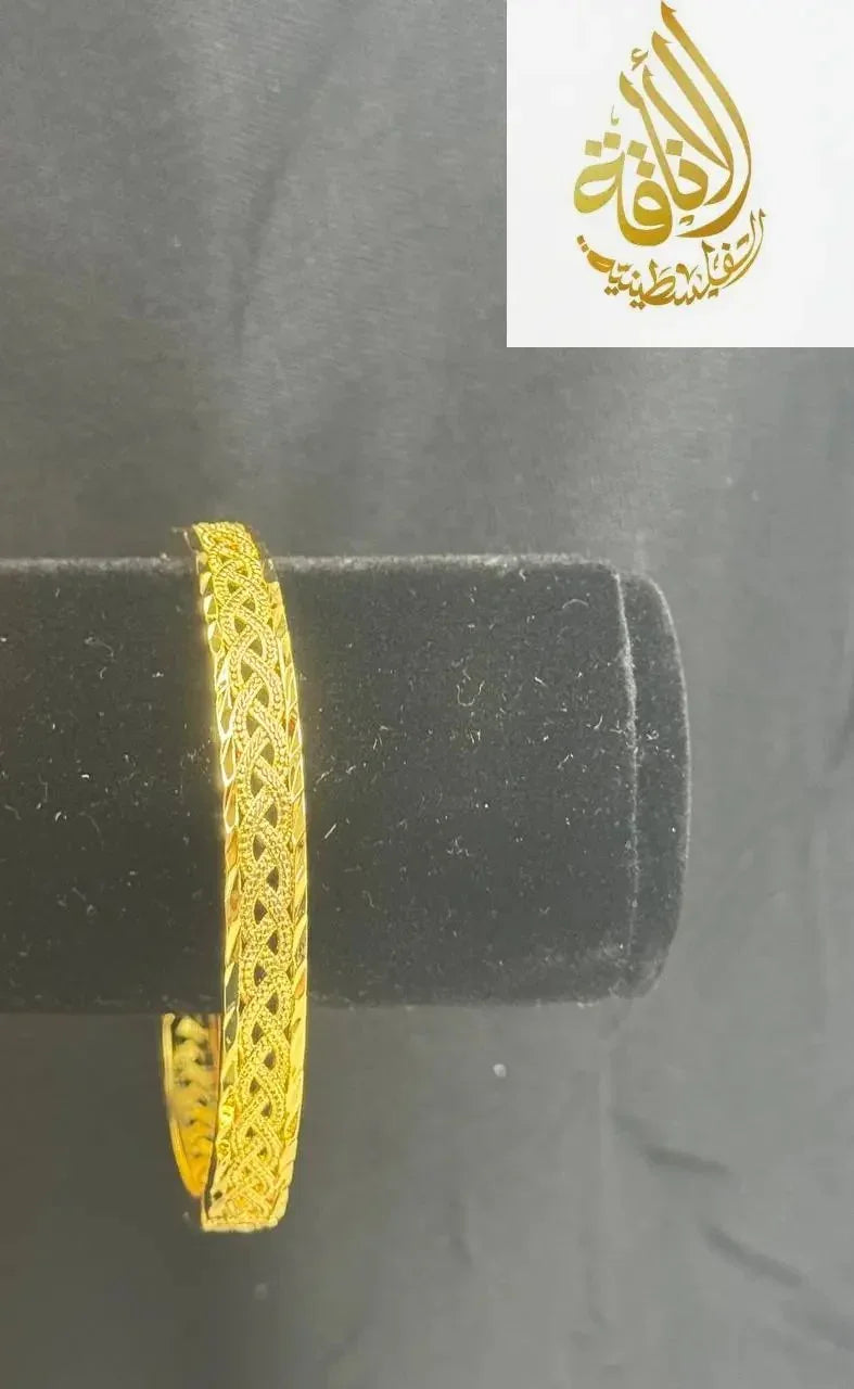 Intricately designed imitation gold bangle bracelet by Palestinian Elegance displayed on black velvet stand