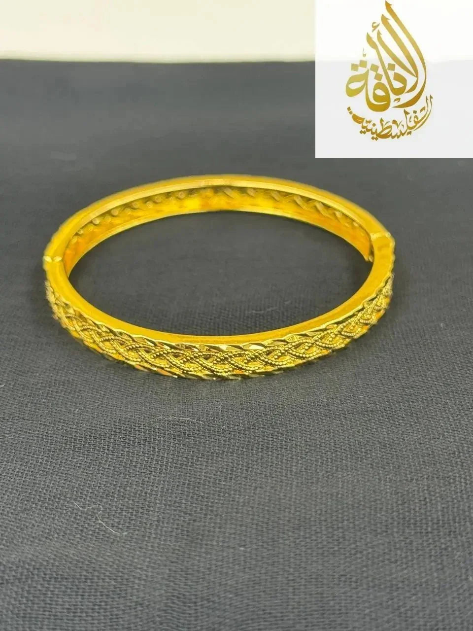 Palestinian Elegance imitation gold bangle bracelet with intricate woven design on black background