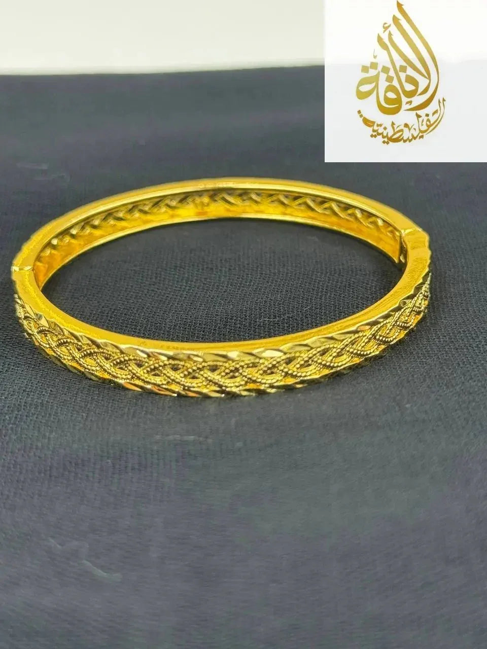 Palestinian Elegance imitation gold bangle bracelet with intricate braided design on black background