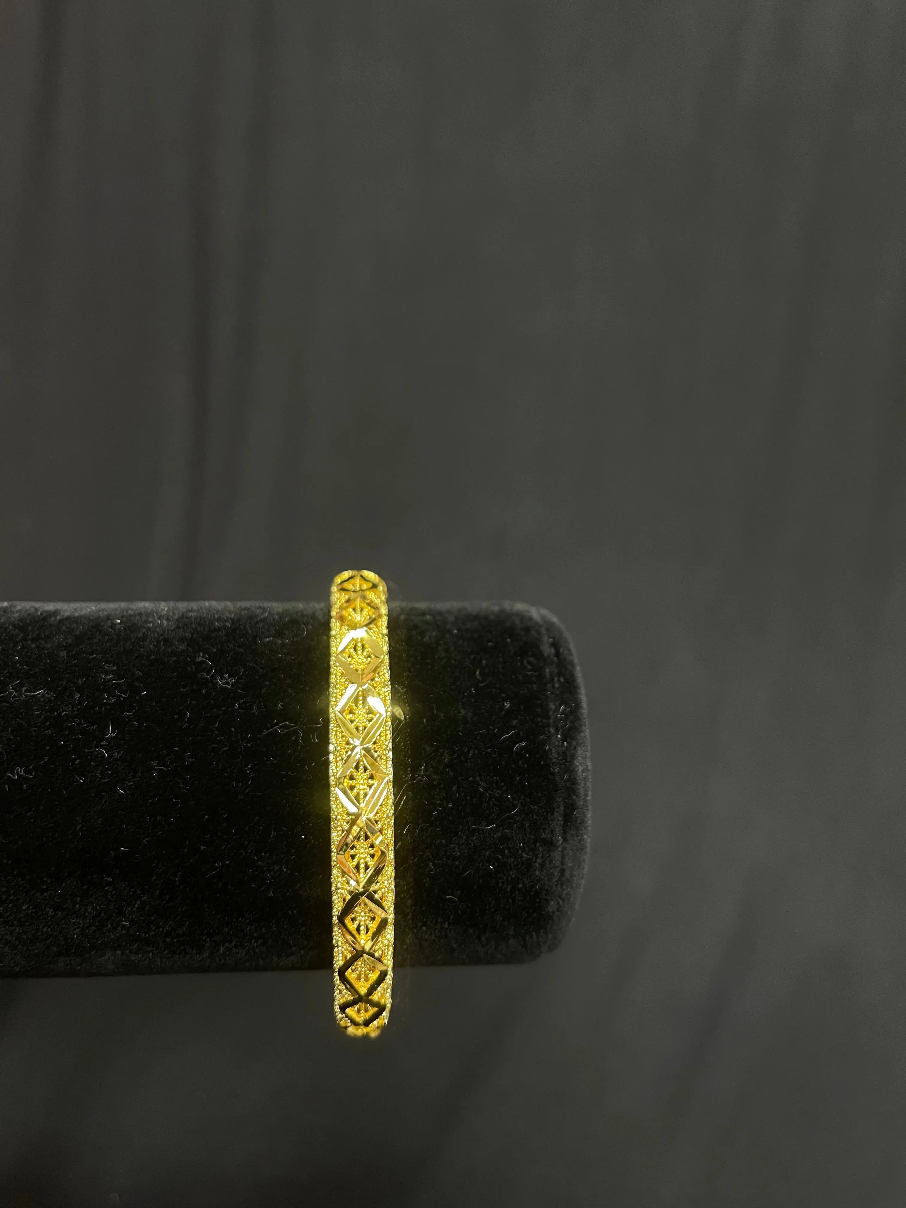 Palestinian Elegance imitation gold bangle with intricate geometric patterns on black display