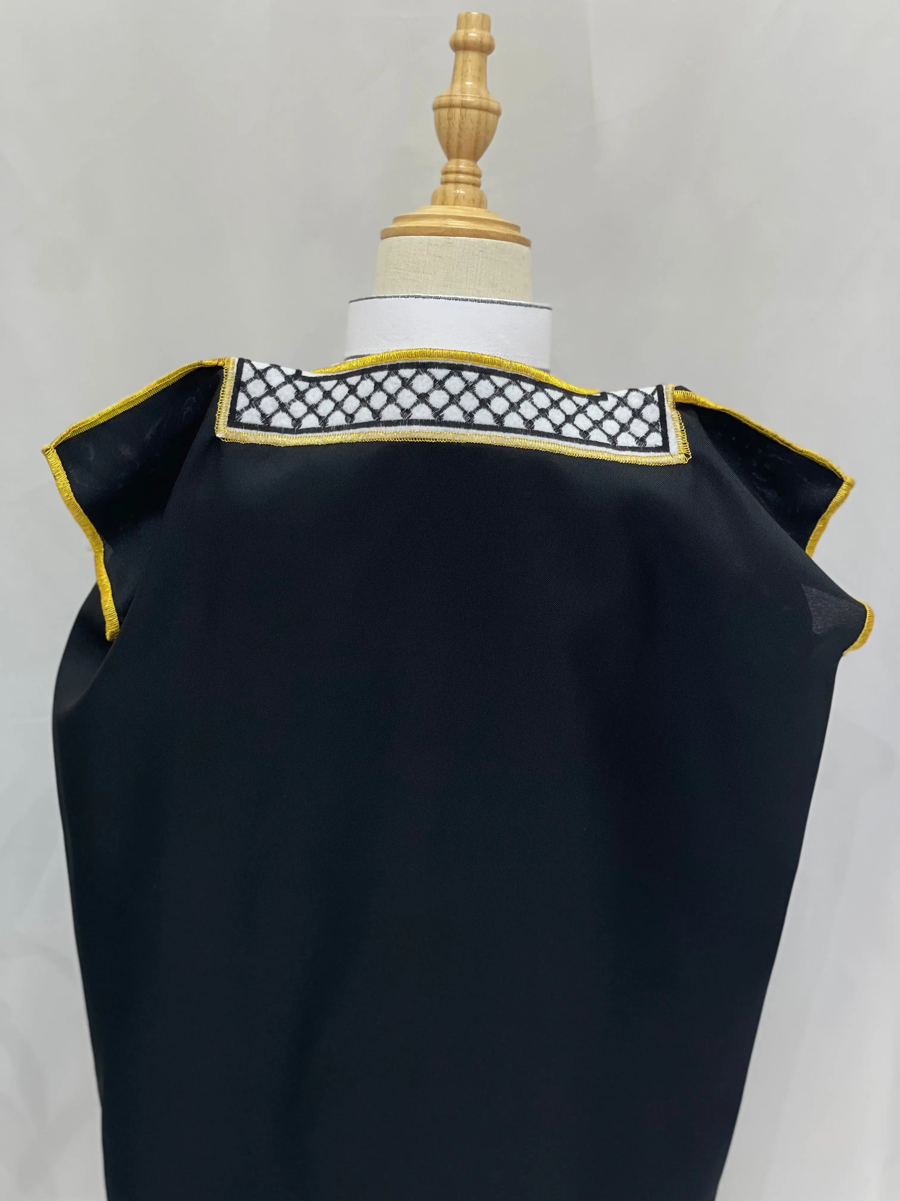 Black Kids Kuffiyeh Bisht with traditional embroidery and gold trim by Palestinian Elegance displayed on mannequin