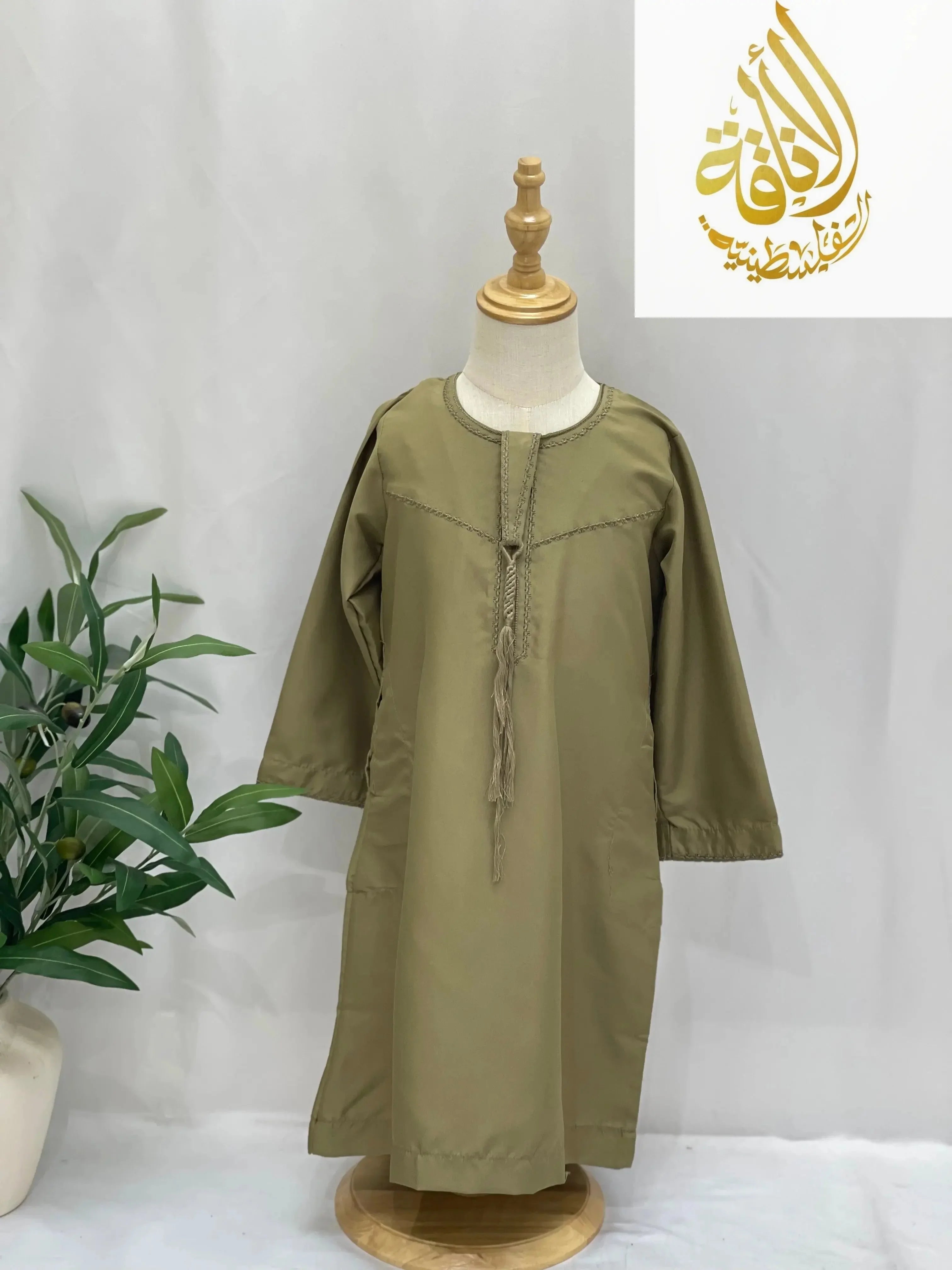 Kids thobe with detachable sharshoba in olive green displayed on a mannequin by Palestinian Elegance