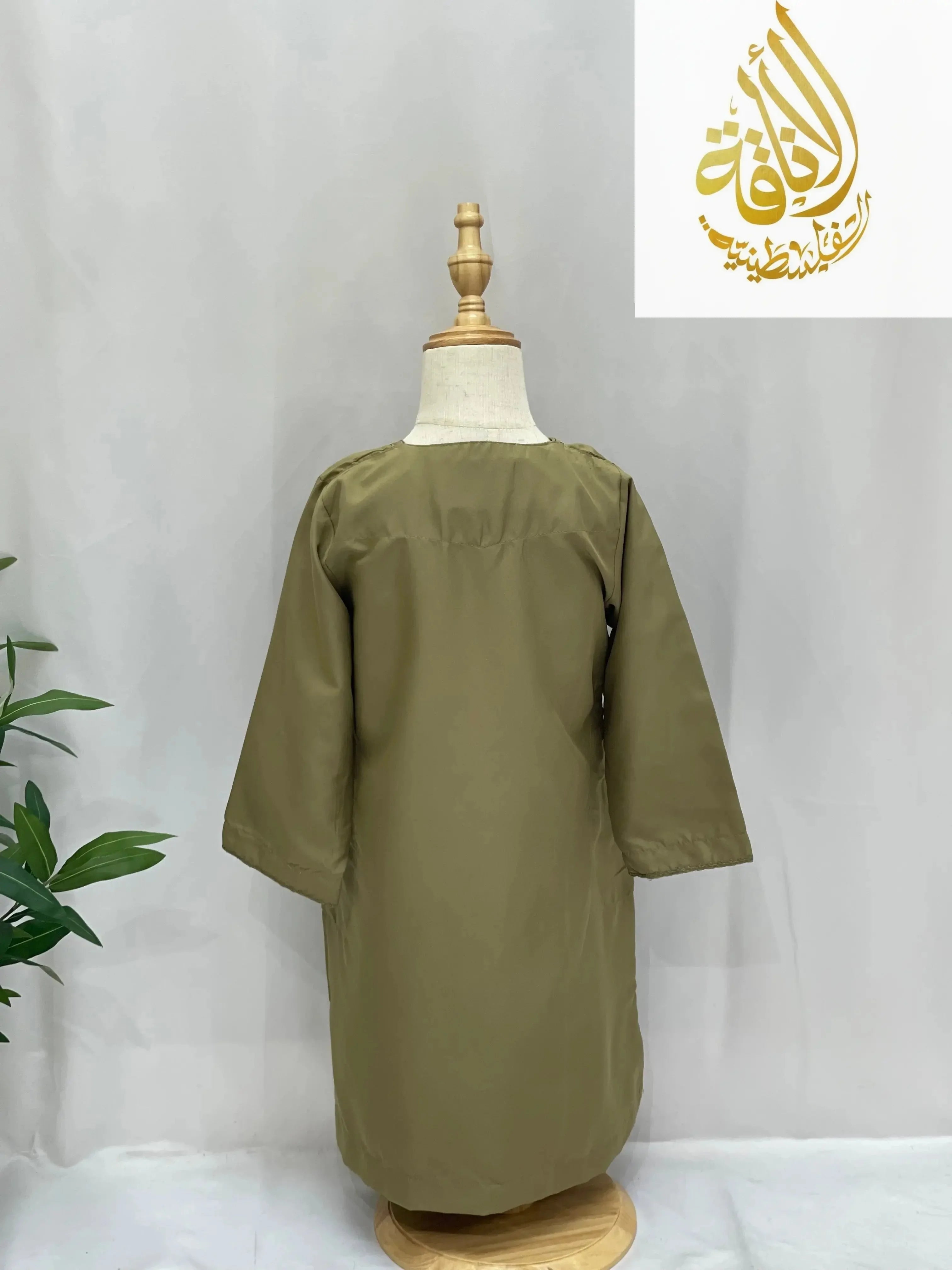 Kids thobe with detachable sharshoba in olive green displayed on a mannequin by Palestinian Eleganc