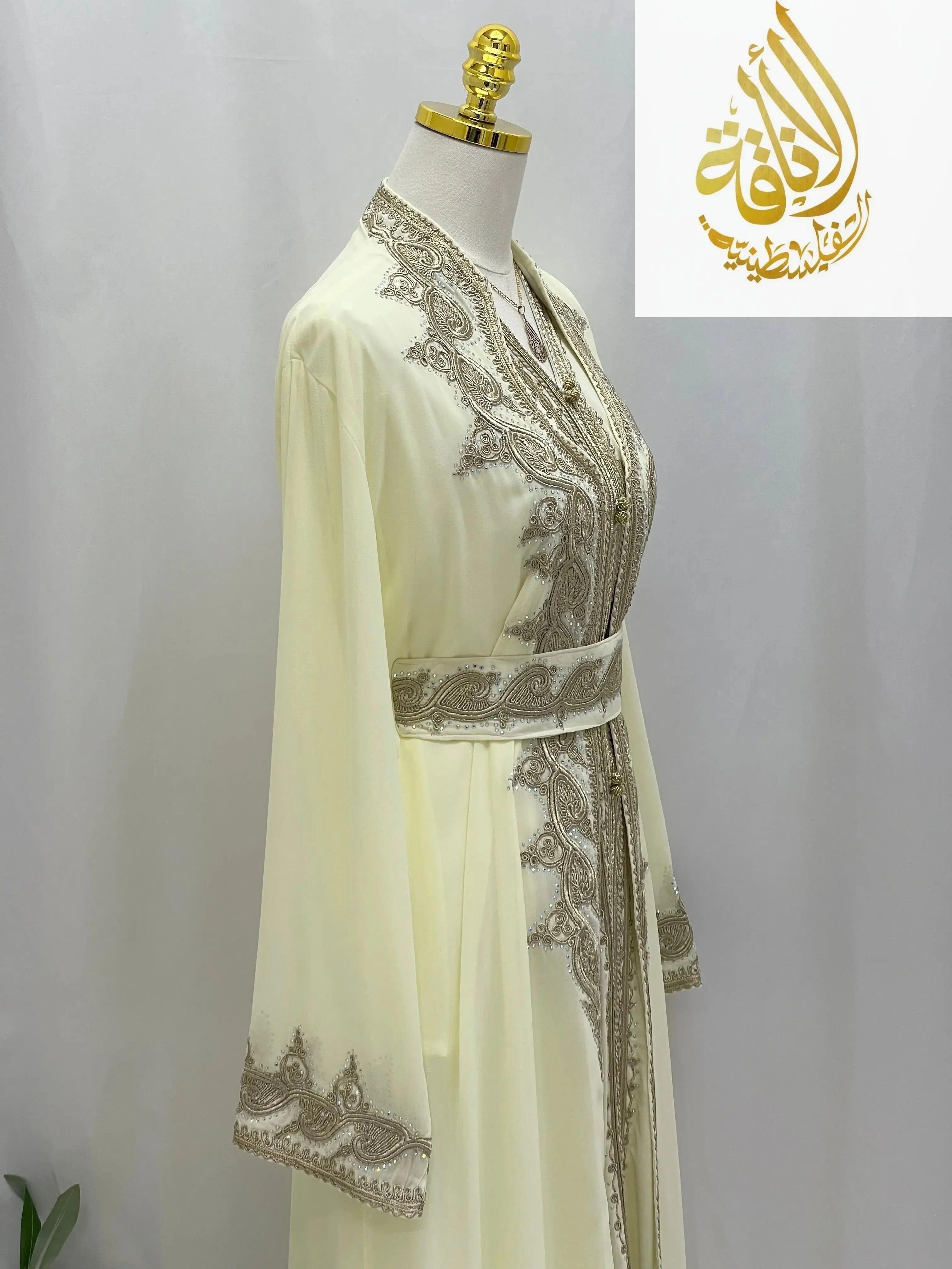 Luxury cream-colored luxurious Alamera kaftan with intricate silver embroidery and matching belt by Palestinian Elegance