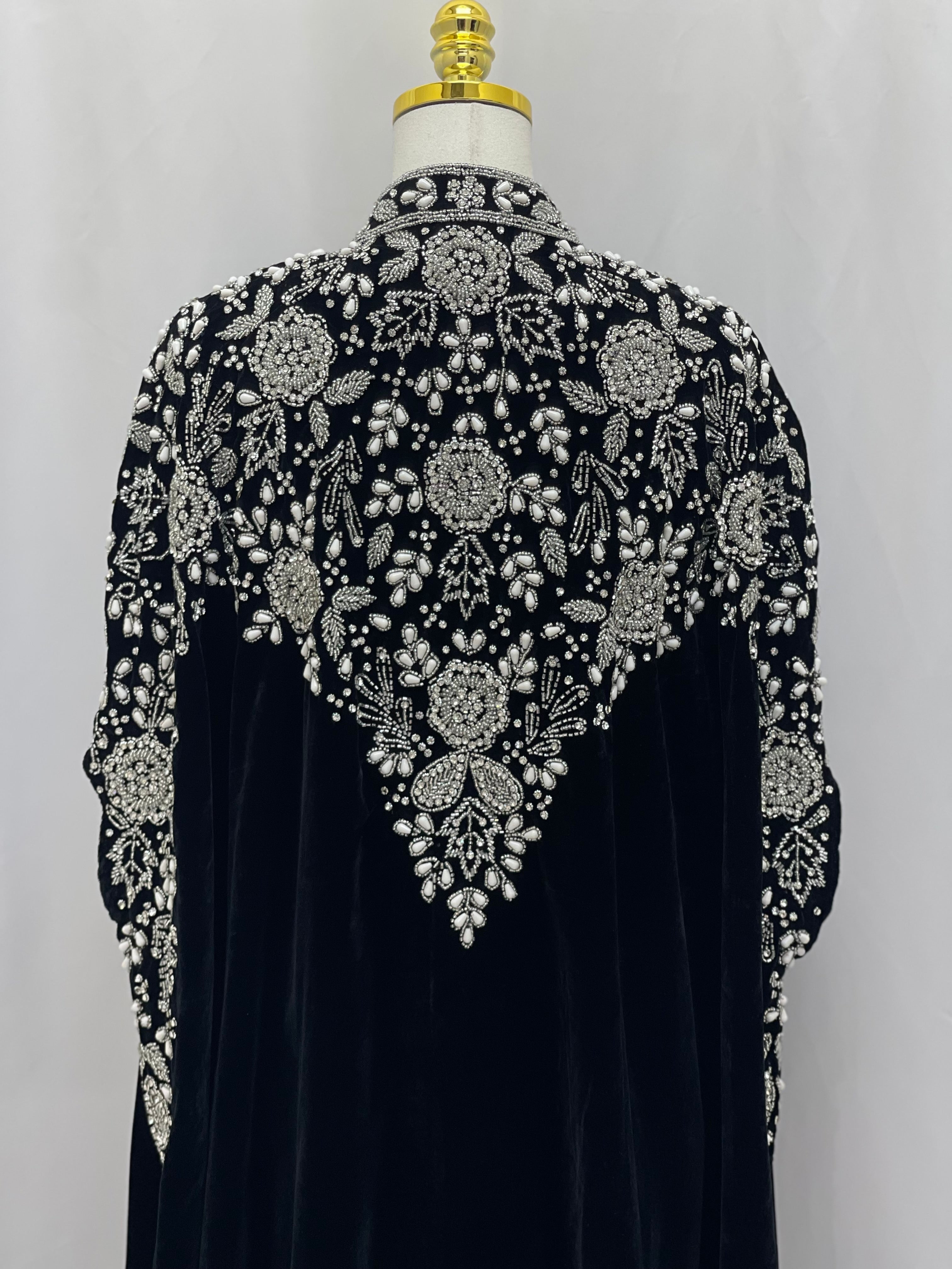 Velvet Embellished Cape cardigan by Palestinian Elegance with intricate silver beadwork and floral designs on black fabric