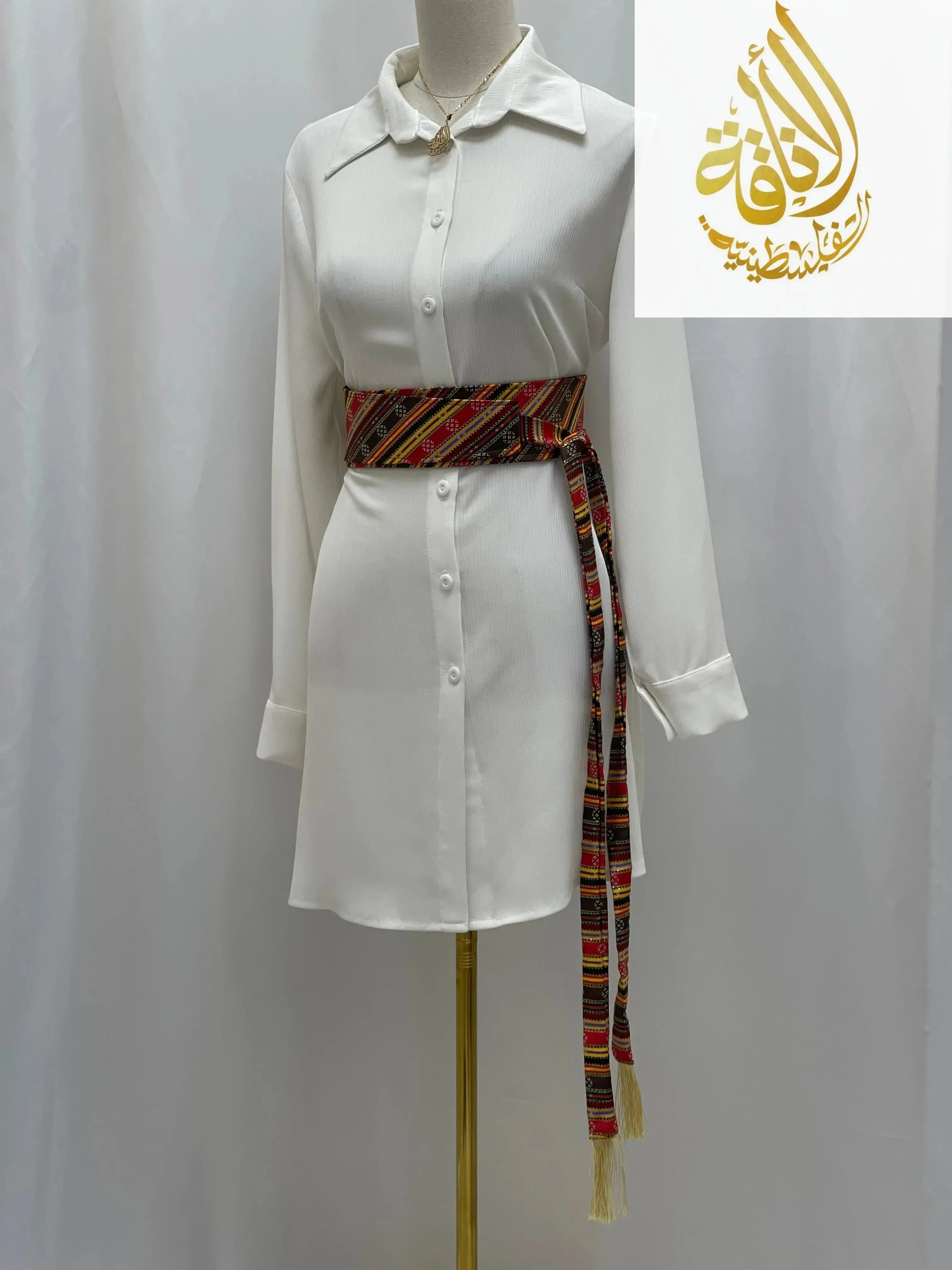 Palestinian embroidered belt in multicolor worn around waist of white button down dress from Palestinian Elegance