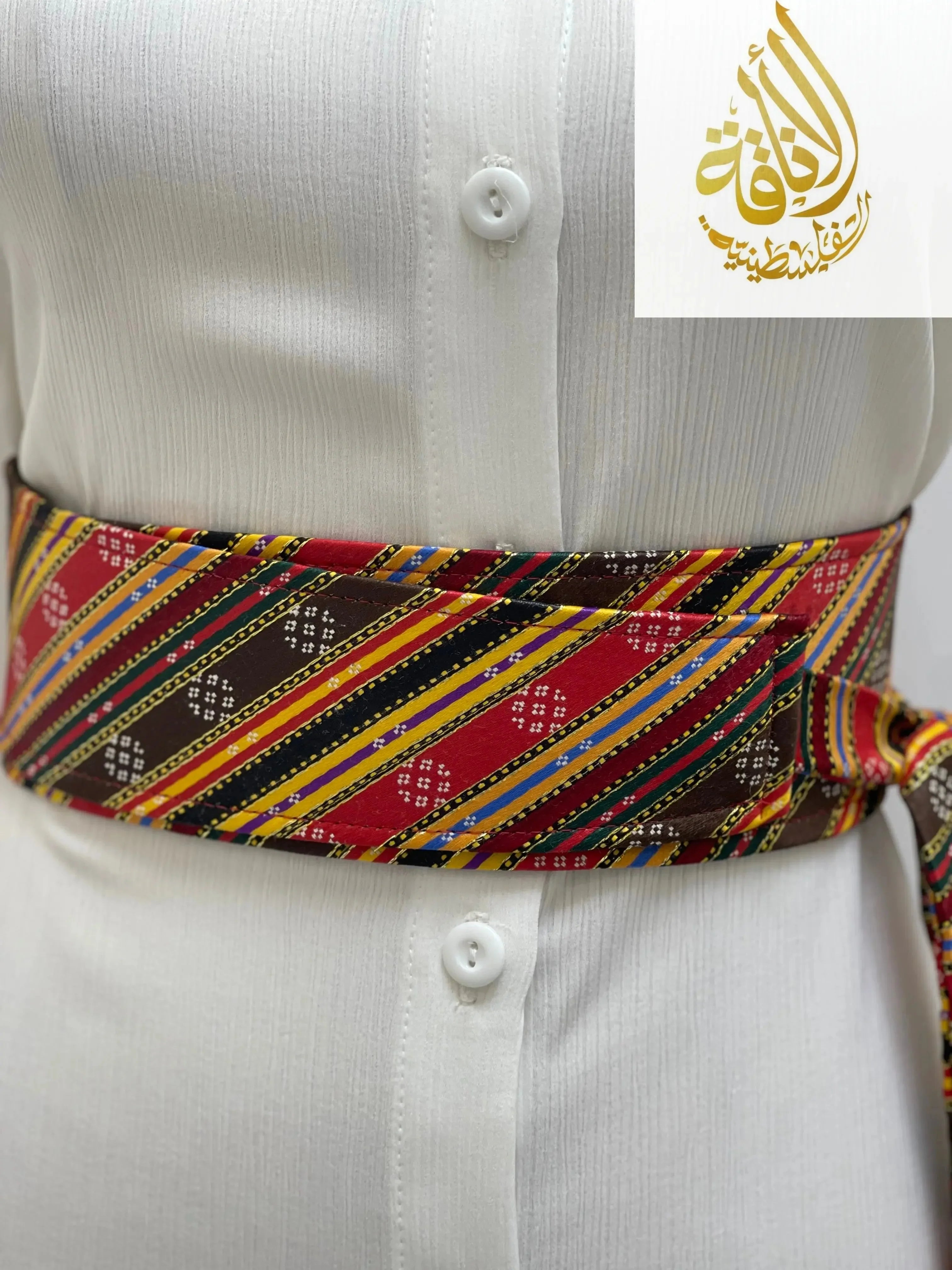 Palestinian embroidered belt in red, yellow, black, and green wrapped around a white shirt waist