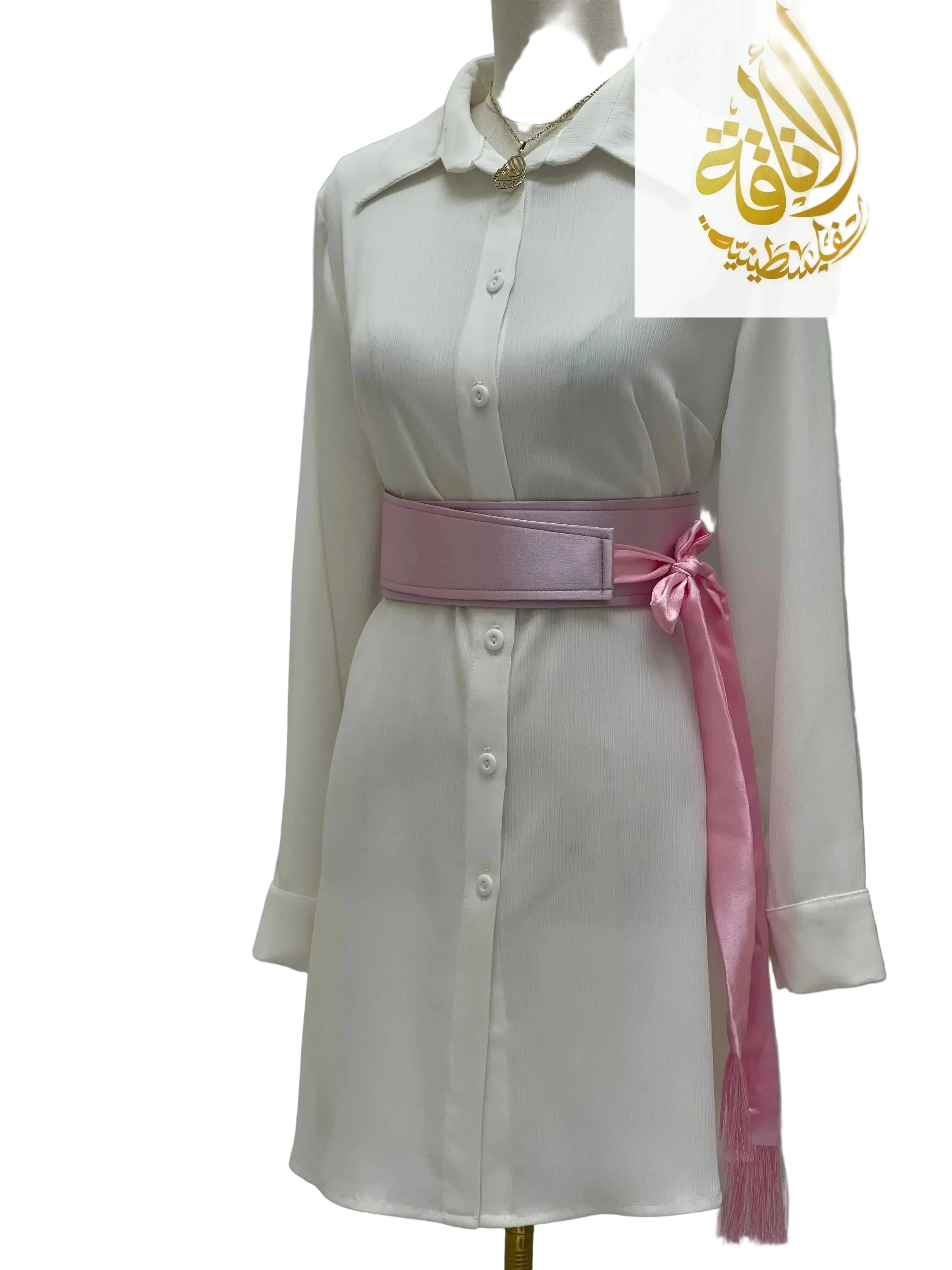 Pink satin belt for dresses tied in a bow over a white button-down dress on mannequin