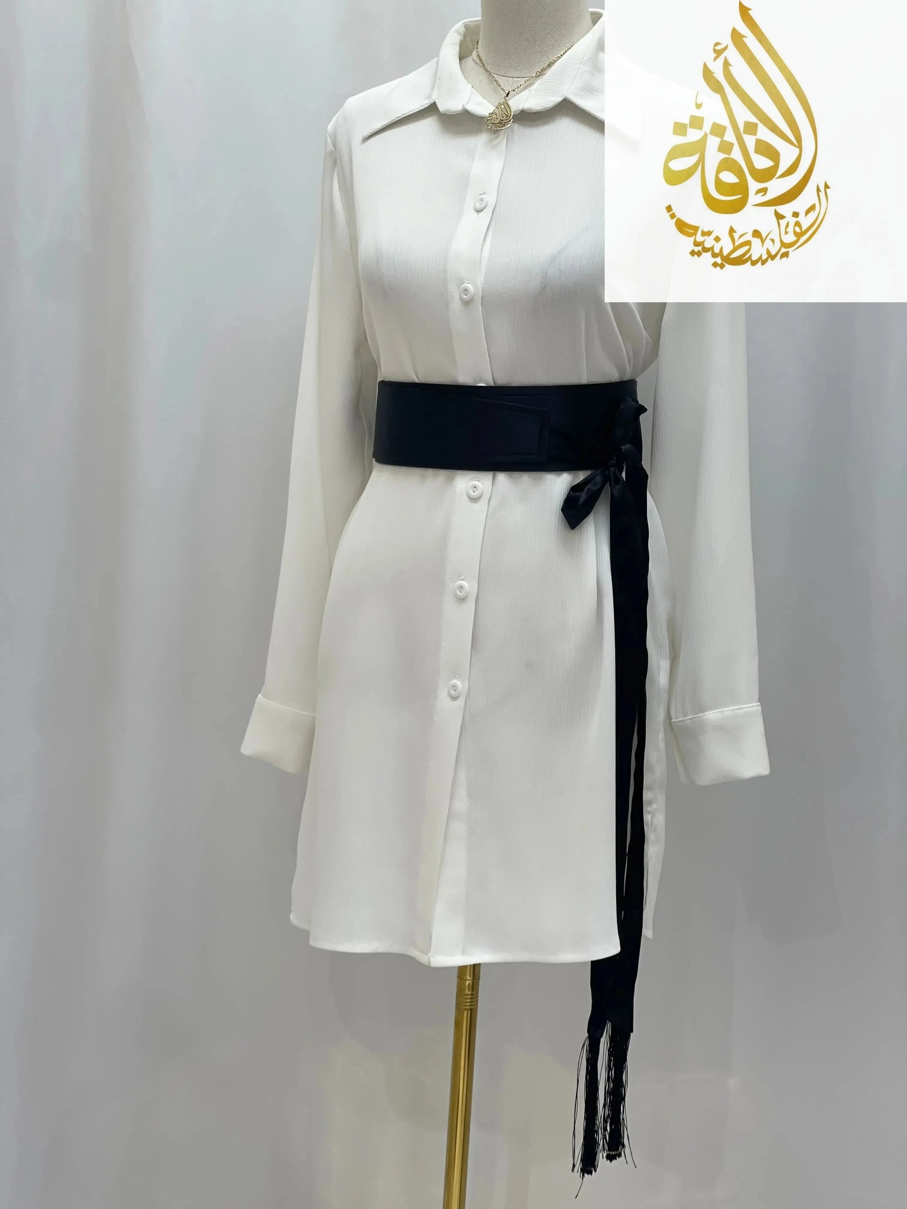 Black satin belt for dresses tied around a white long-sleeve button-down dress on a mannequin