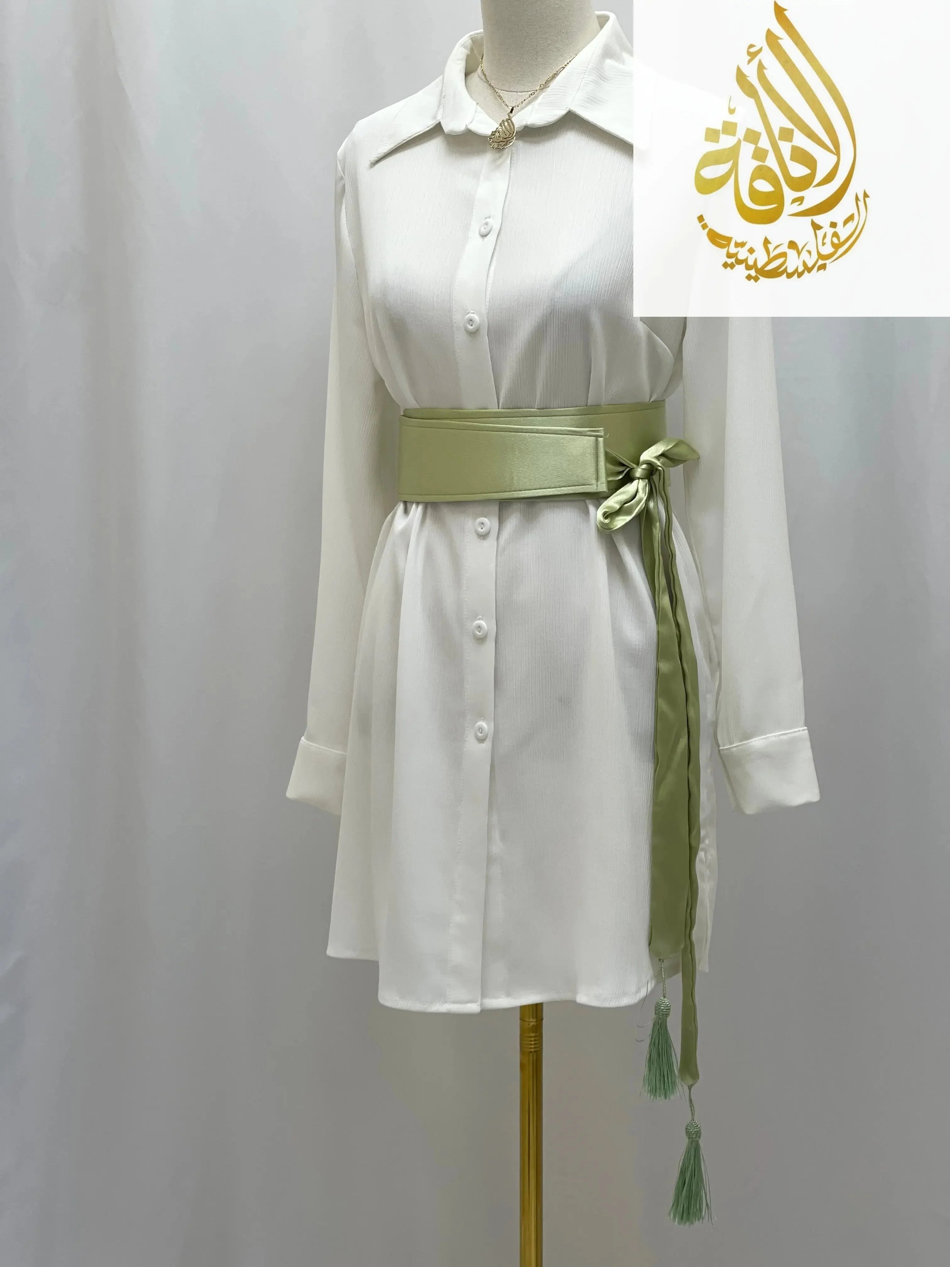 Green satin belt for dresses tied around white button-down shirt dress by Palestinian Elegance