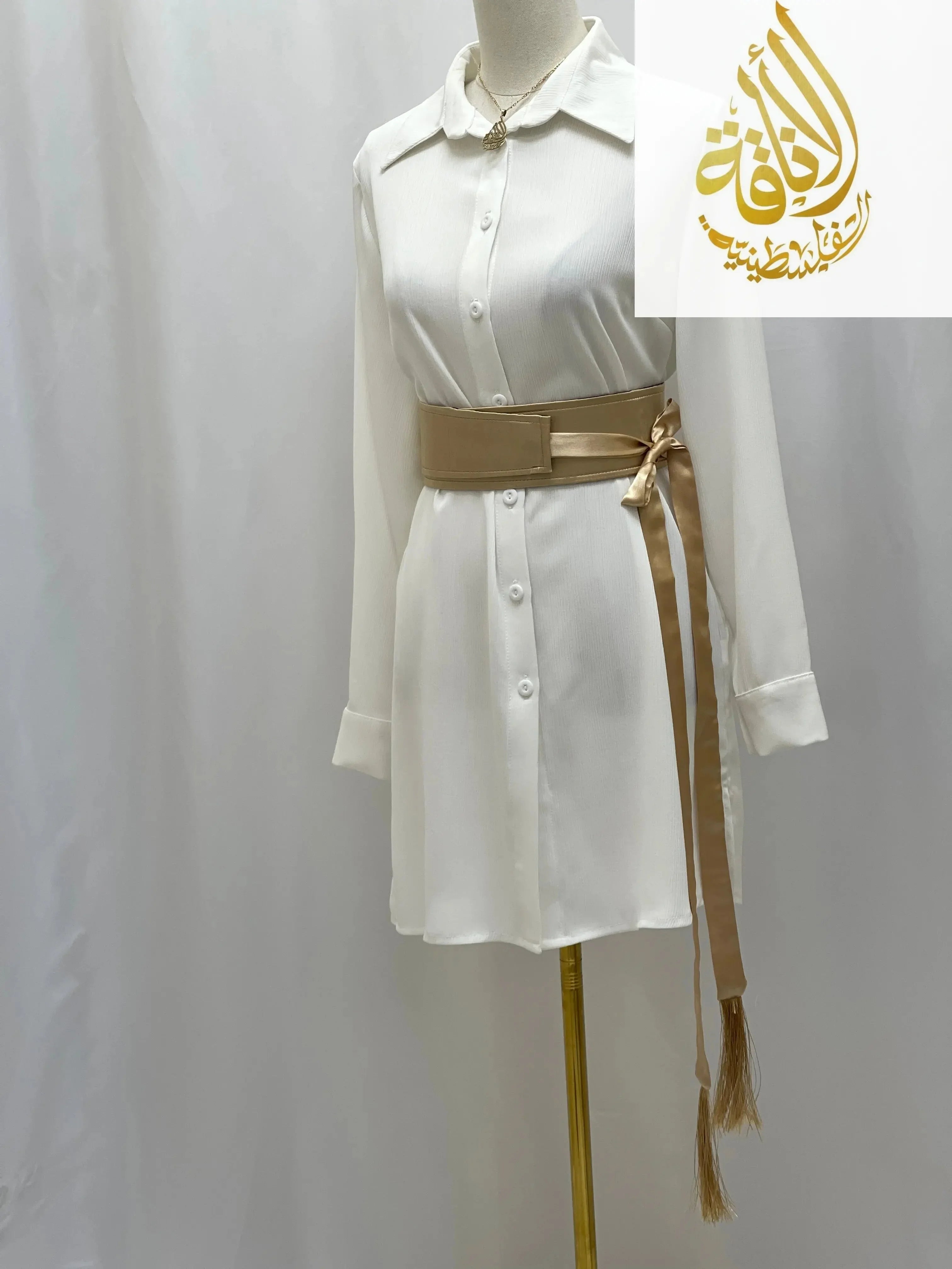 Palestinian Elegance satin belt for dresses in gold tied around a white button-up dress on mannequin
