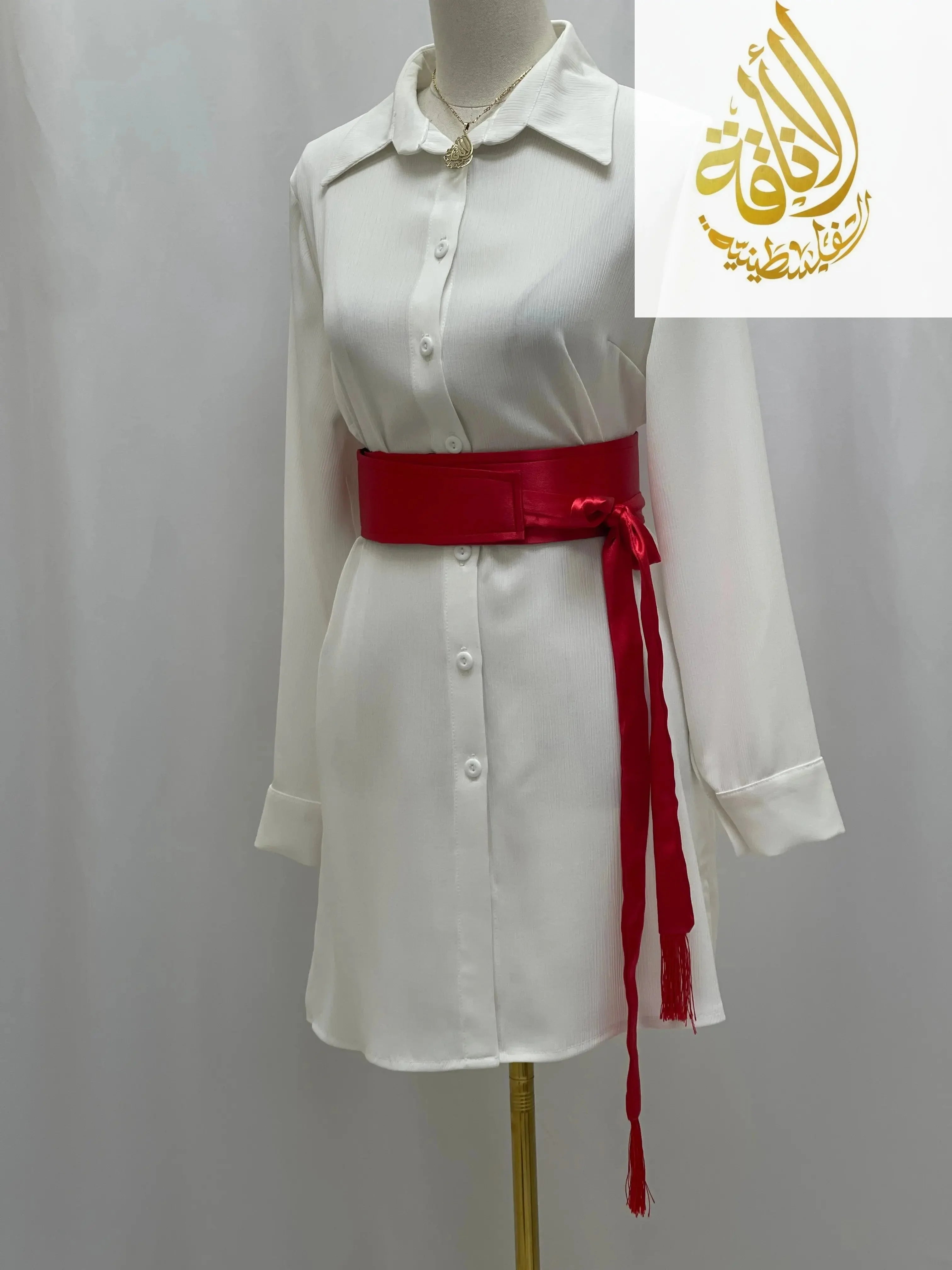Red satin belt for dresses tied around waist of white button-down dress by Palestinian Elegance