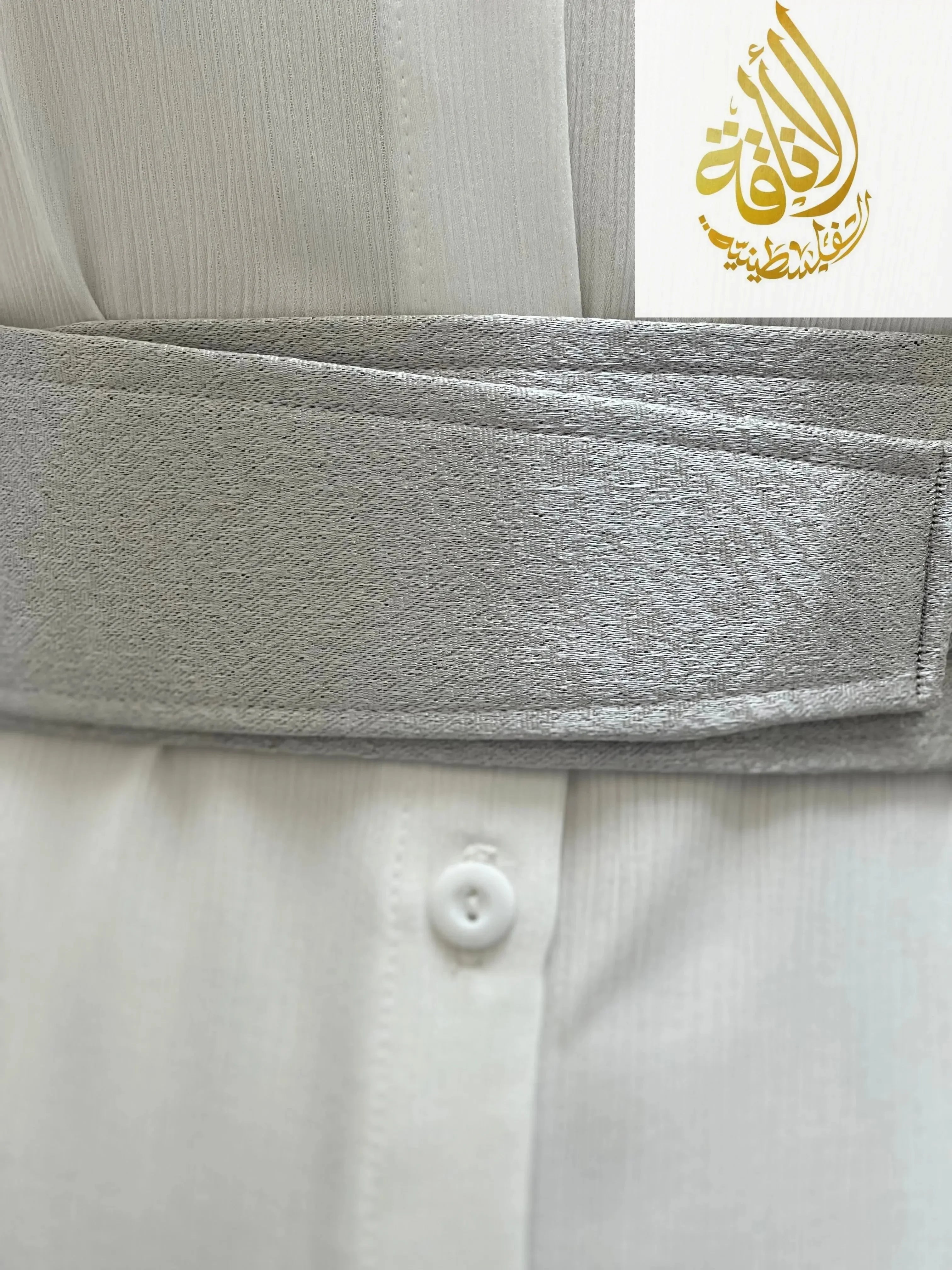 Gray satin belt for dresses by Palestinian Elegance wrapped around a white pleated dress