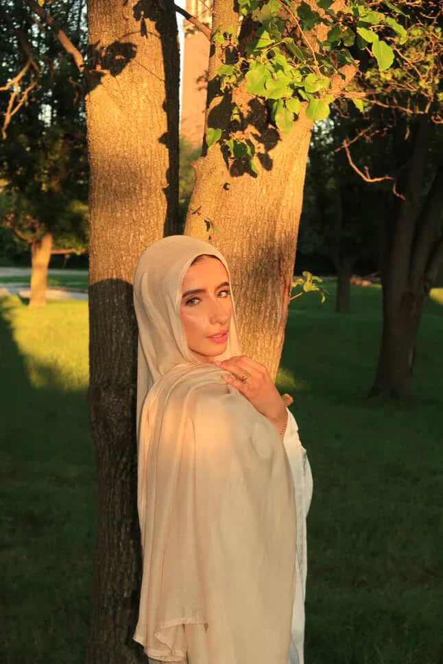 Palestinian Elegance New Modal Hijab light beige draped on model leaning against tree in sunlit park