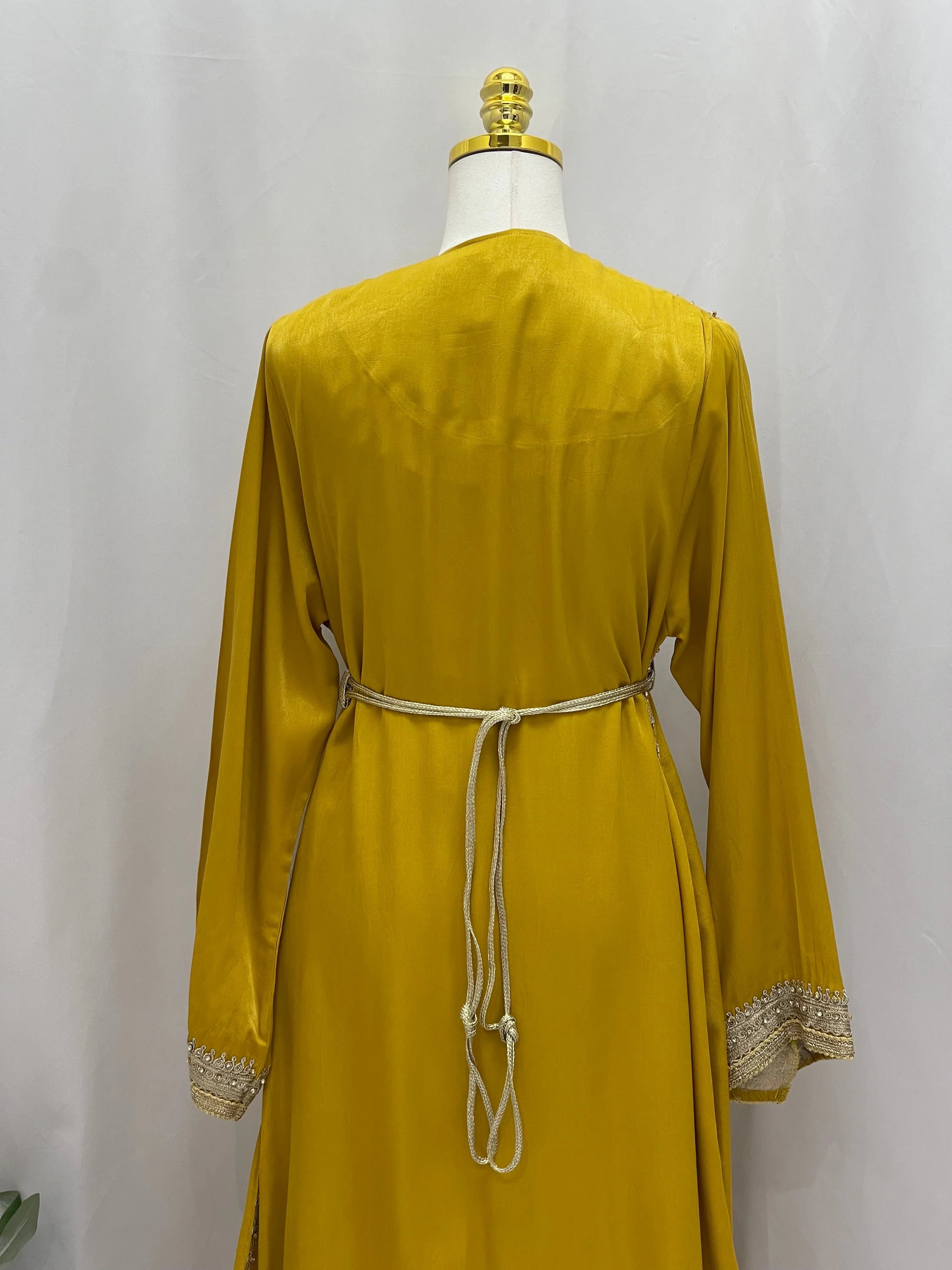 Back view of Omima Morocco Style Kaftan in mustard yellow with embroidered cuffs and tied waist belt