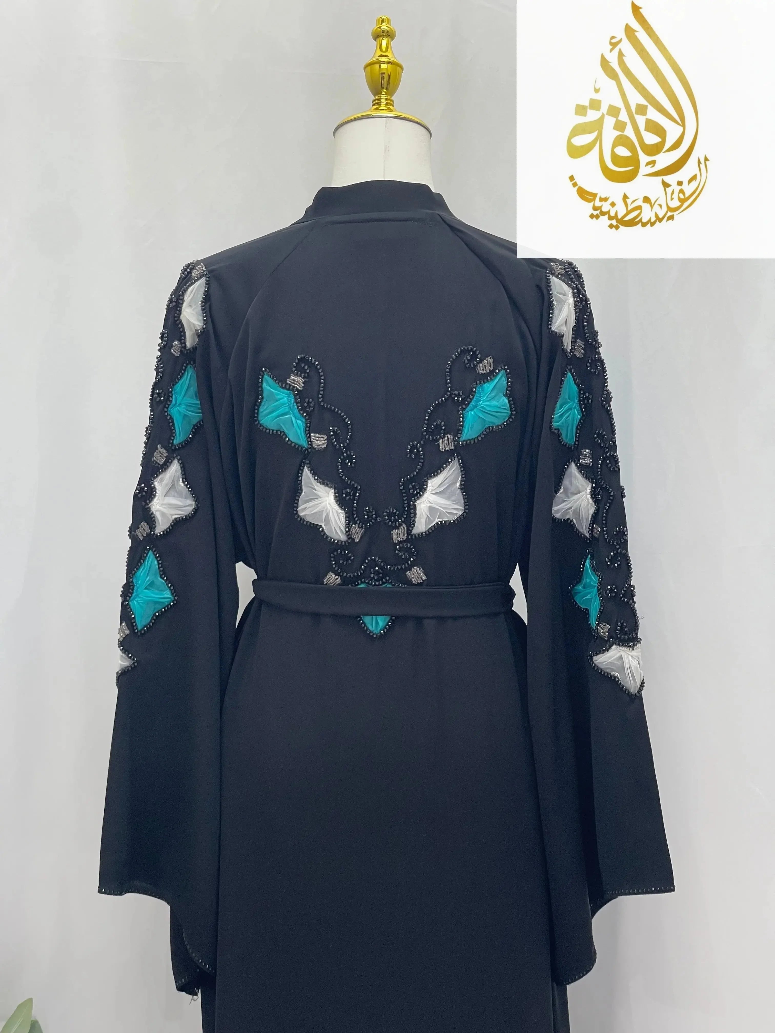 Back view of elegant black abaya with turquoise and white embroidered details on sleeves and back