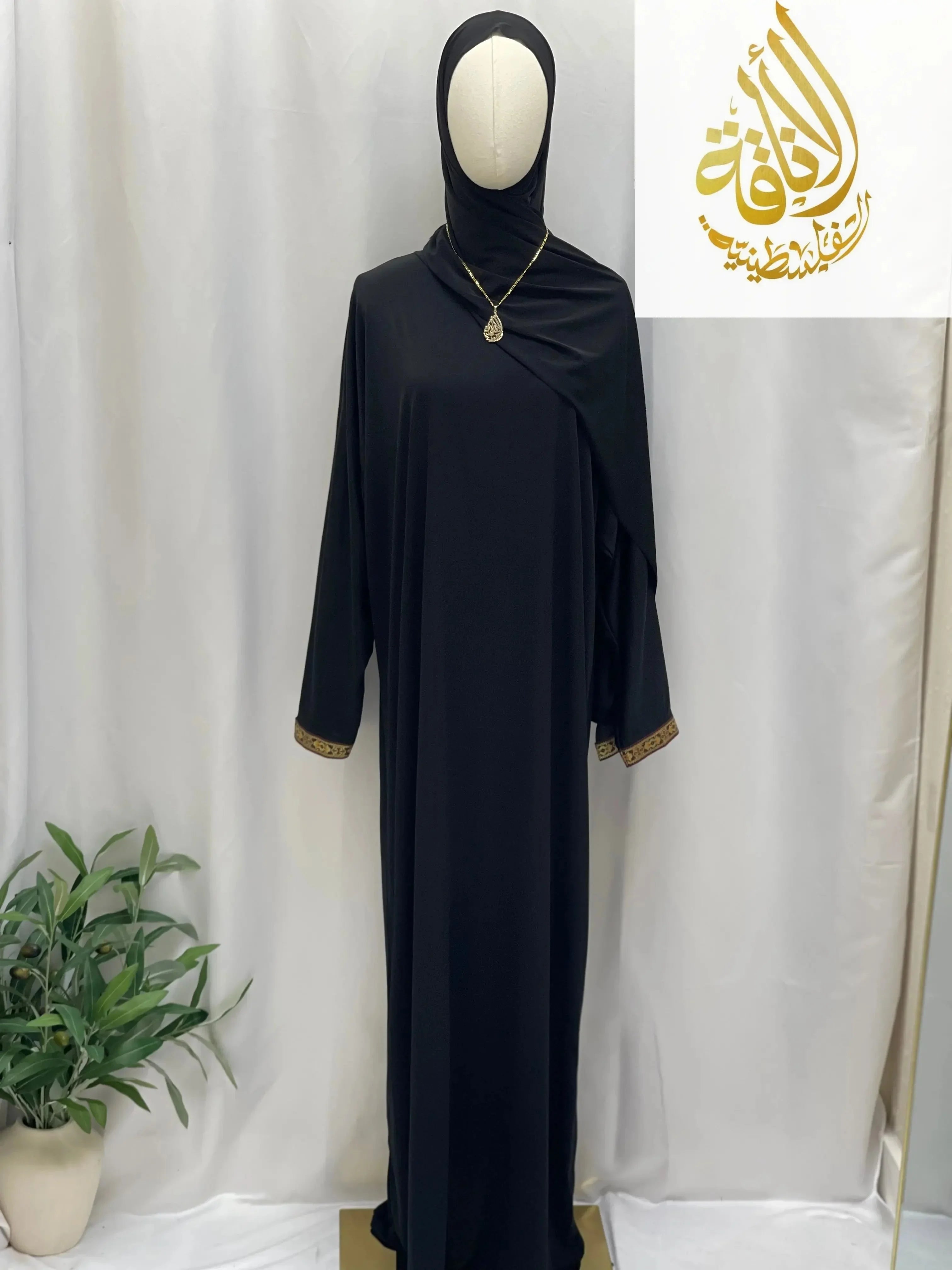 Palestinian Elegance black abaya one piece prayer dress with gold cuff details displayed on mannequin